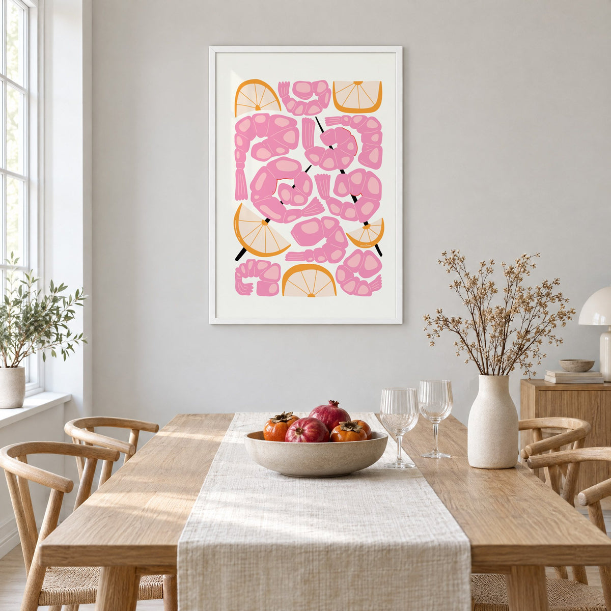 pink shrimp skewers orange wedges print in a white frame above a light oak dining table with a linen runner and fruit bowl