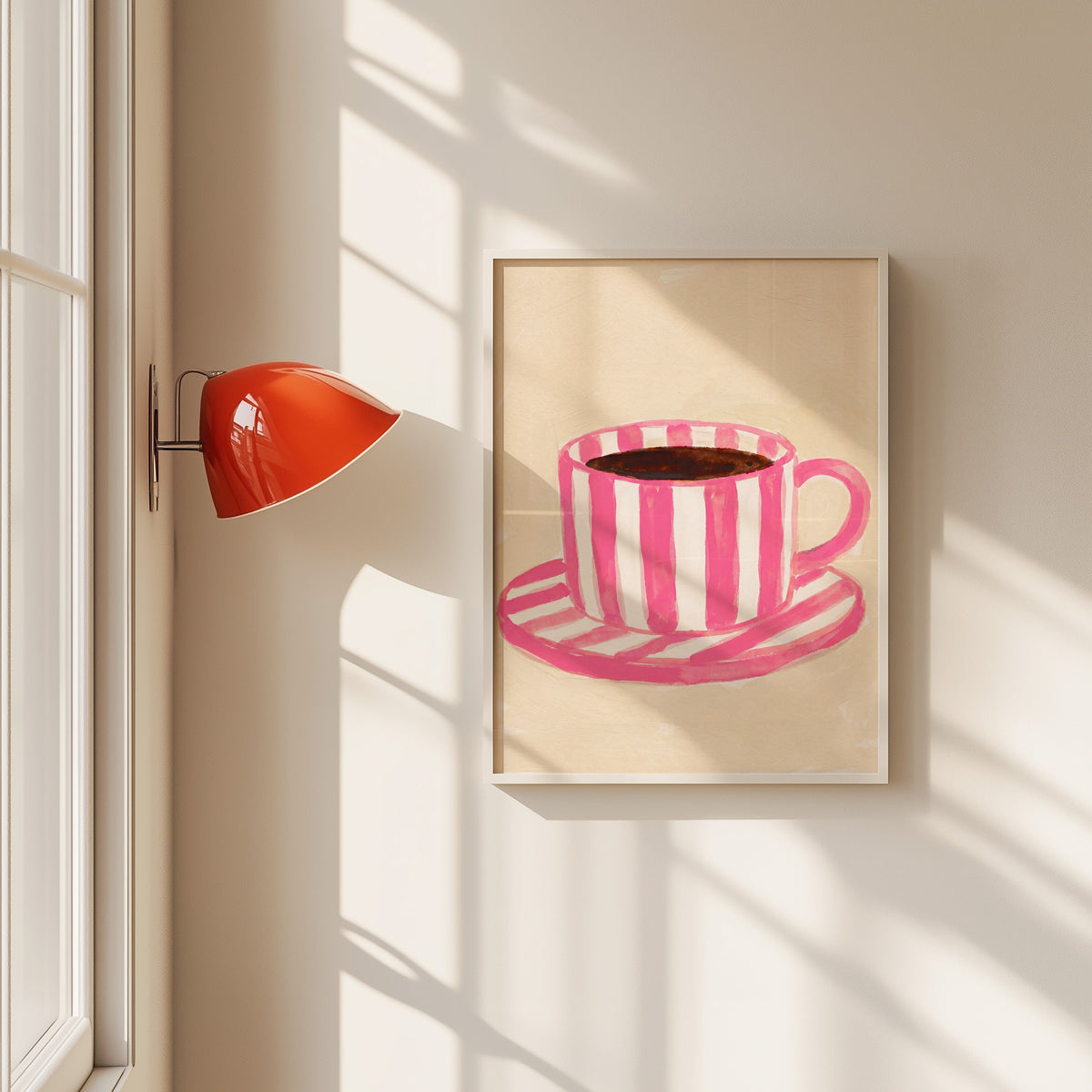 Pink striped coffee cup print in a white frame beside a red wall sconce