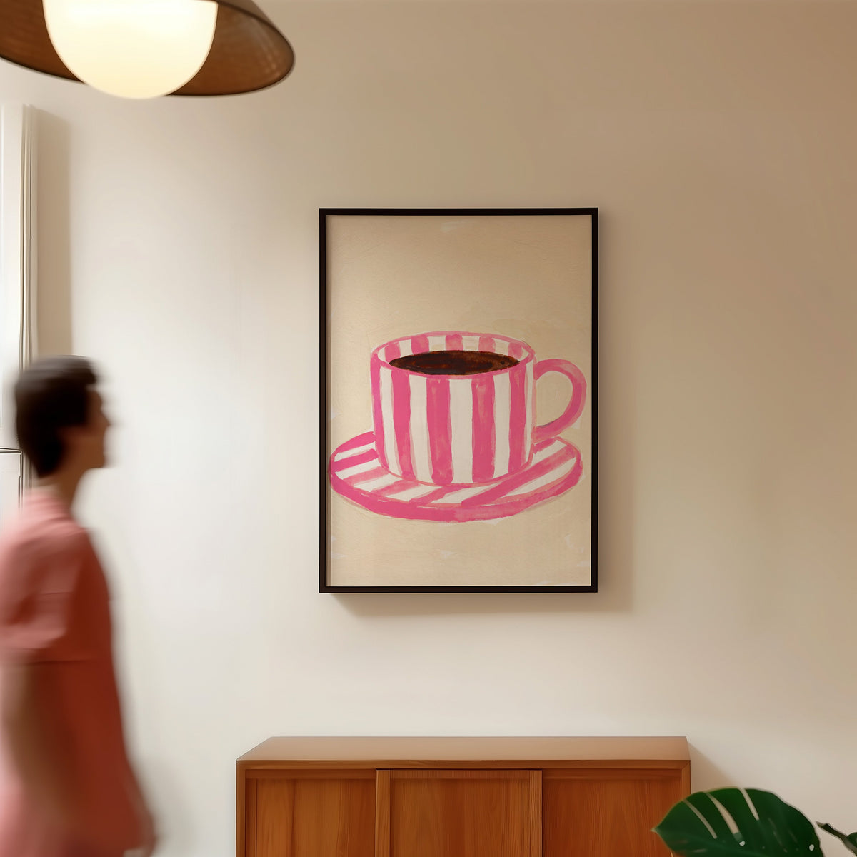 Pink coffee wall art print in a black frame in a hallway under a rattan pendant