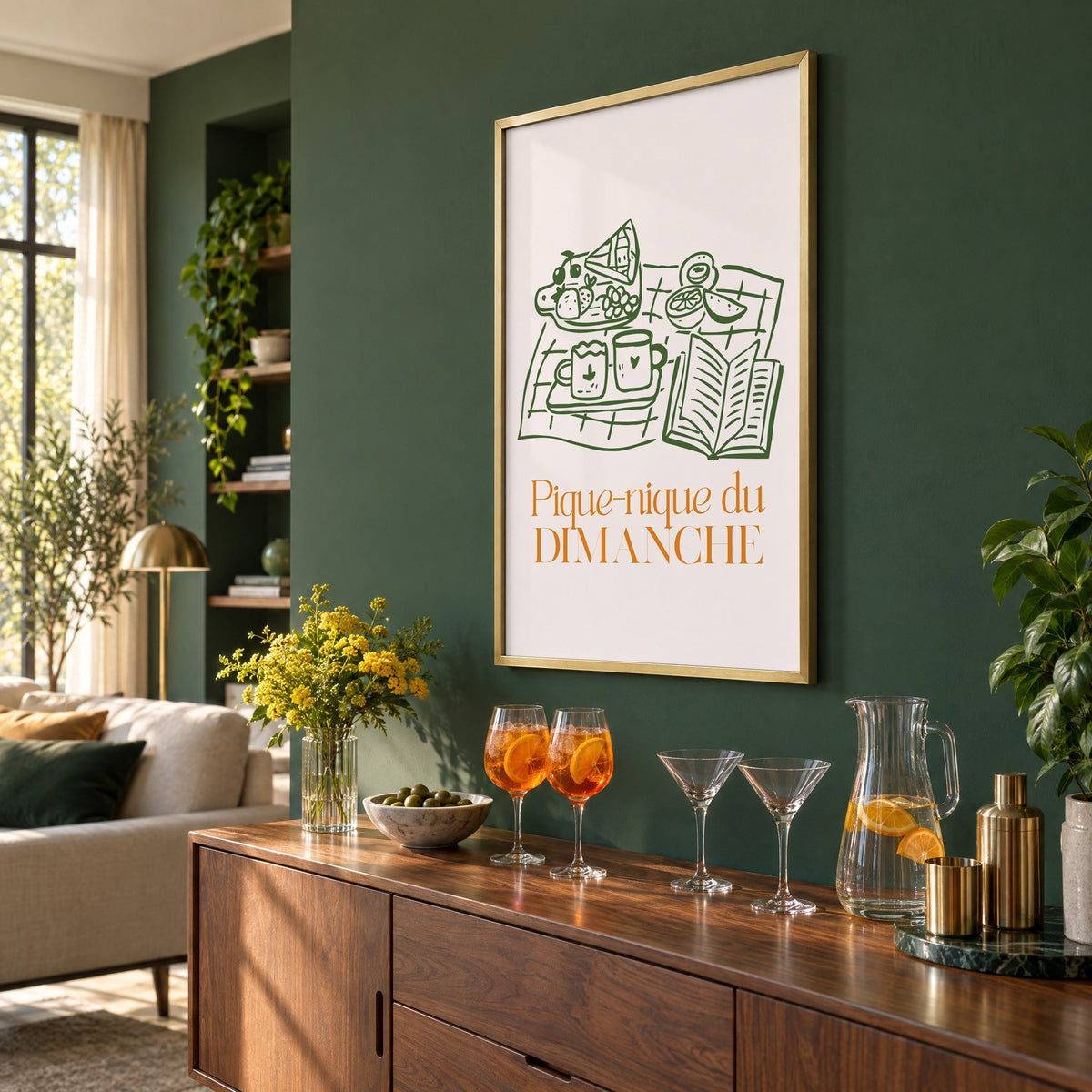 Pique-nique du DIMANCHE picnic line print in a brass frame on a bottle green wall above a sideboard with spritz and martini glasses, seen at an angle