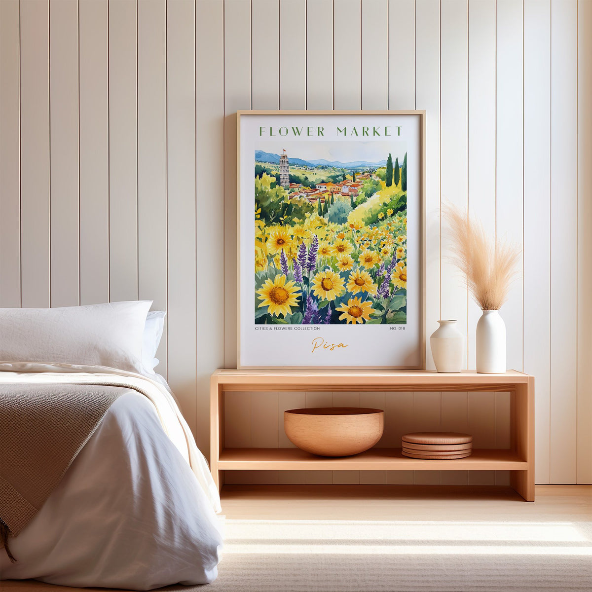 Pisa flower market print in an oak frame on a wood bench against a white shiplap bedroom wall with pampas grass