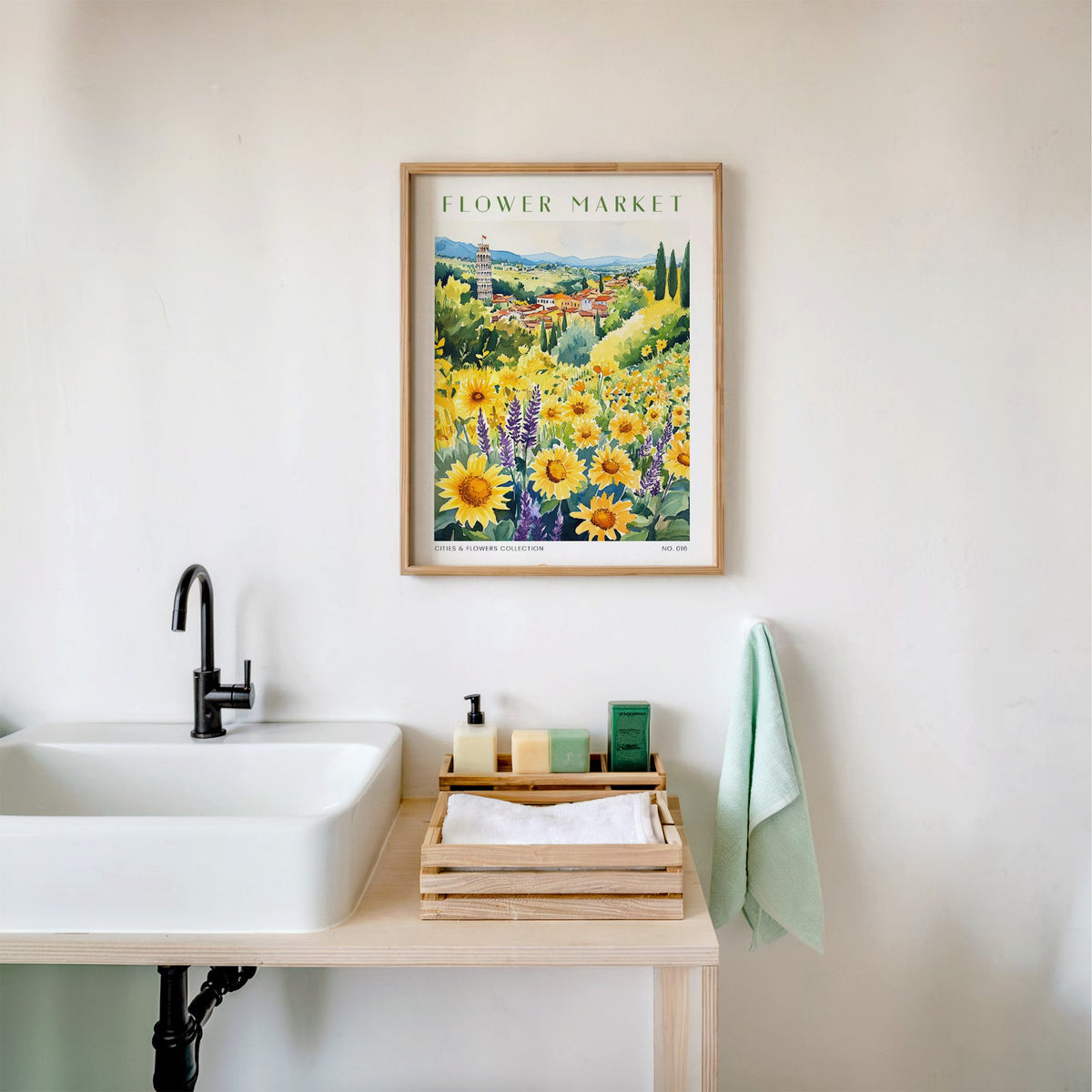 Pisa flower market print in an oak frame above a white bathroom sink with folded towels