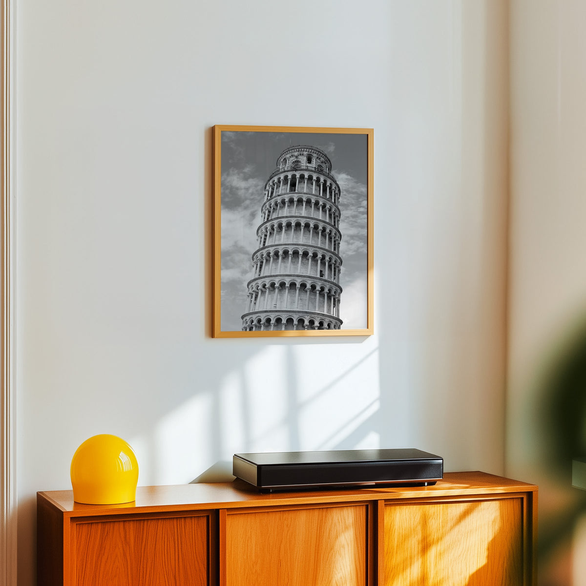 Leaning Tower of Pisa arcades from below print in an oak frame above a teak sideboard with a yellow glass lamp