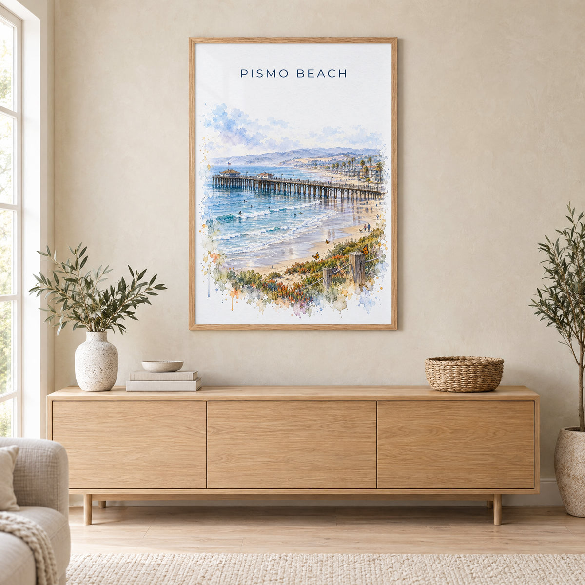 Pismo Beach watercolor print in an oak frame above a light wood sideboard in a Scandinavian living room