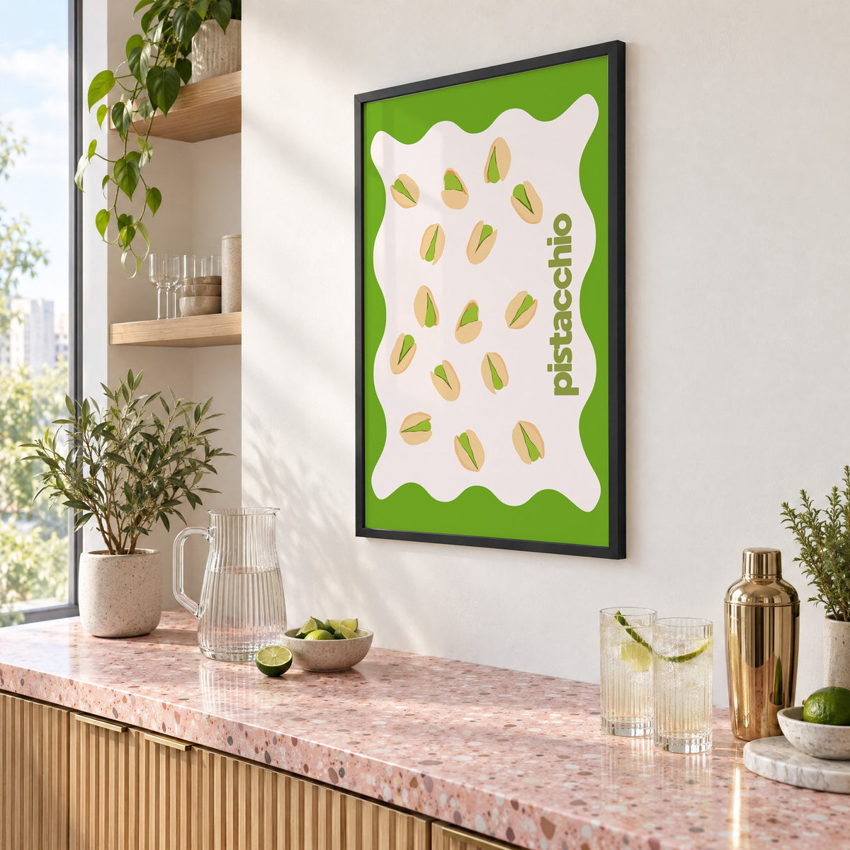 pistacchio vertical type pistachio nuts print in a black frame above a pink terrazzo cocktail counter with limes, seen at an angle