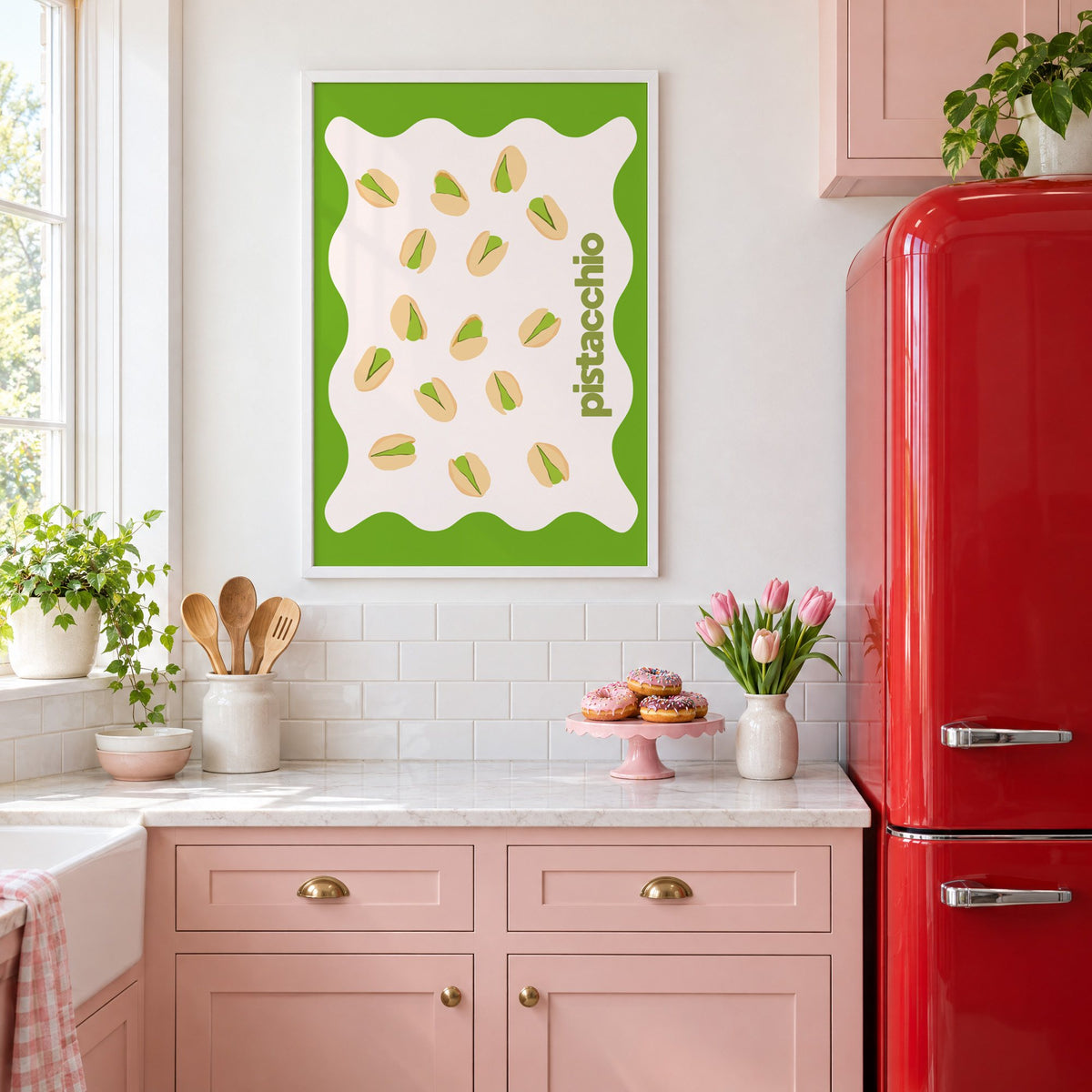 pistacchio vertical type pistachio nuts print in a white frame above pink cabinets beside a red retro fridge