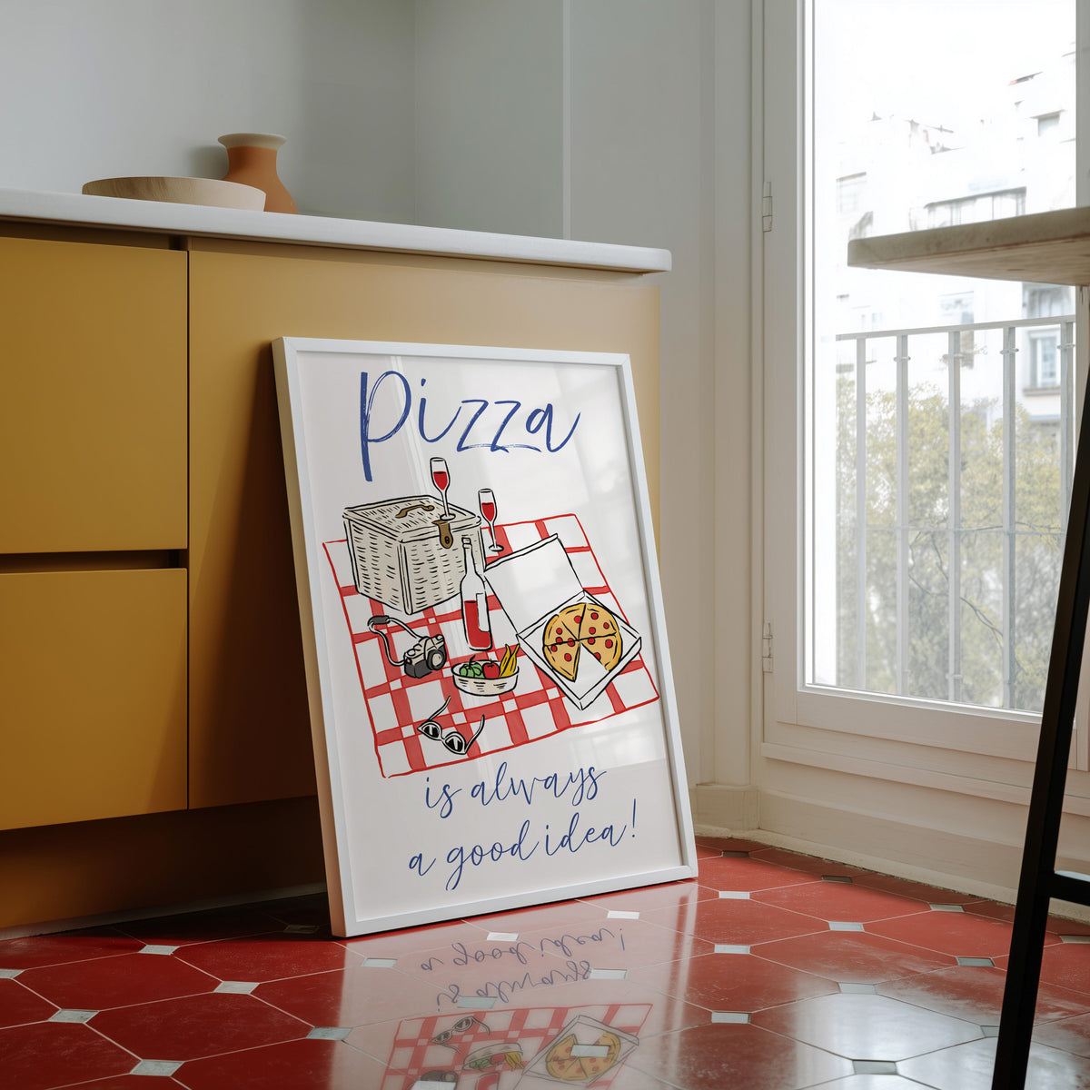 Pizza picnic print in a white frame against yellow cabinets on a red tiled floor