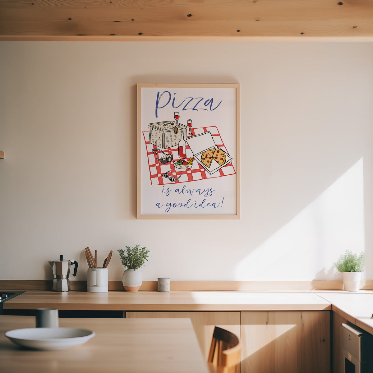 Pizza picnic print in an oak frame above a wood counter with a moka pot and herbs