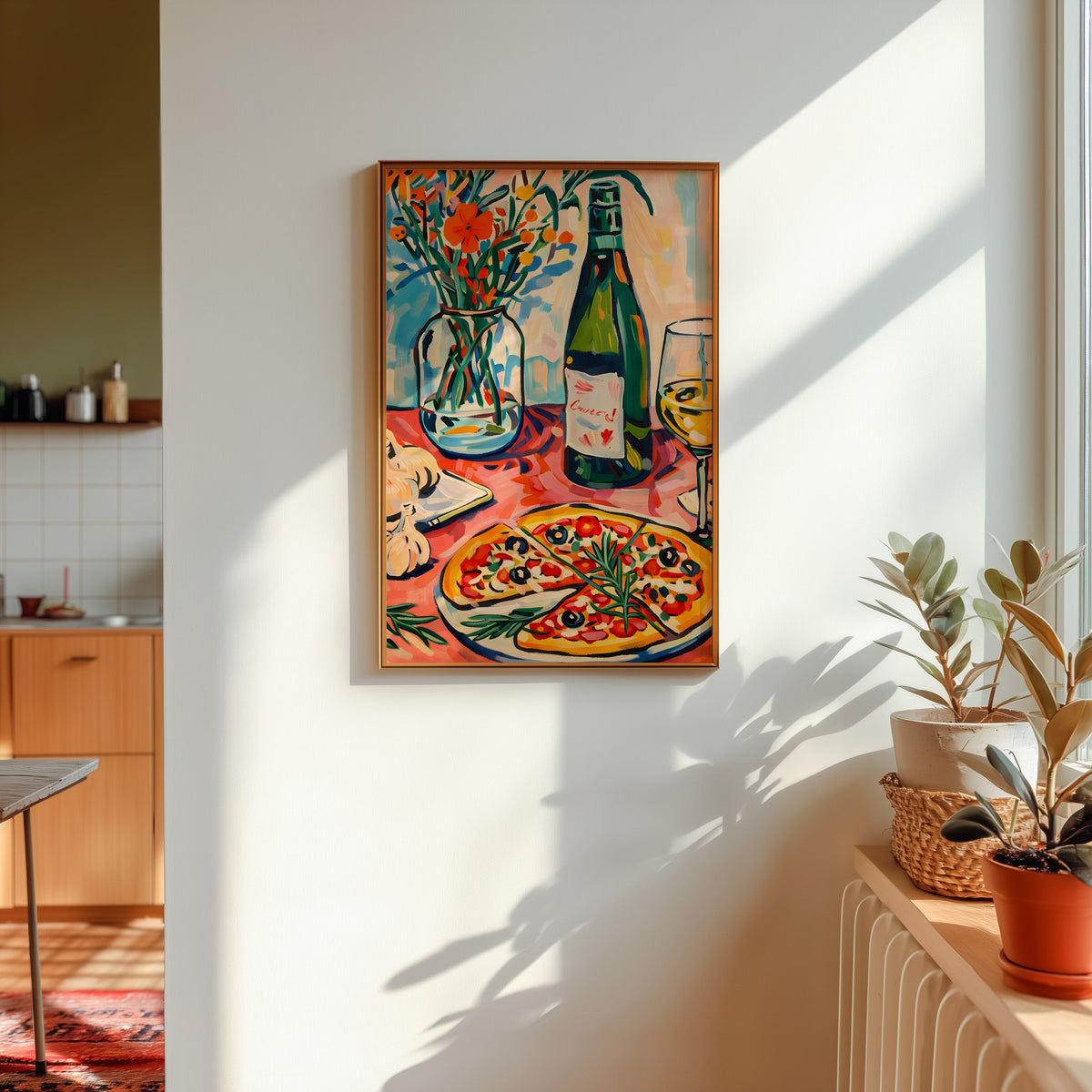 Pizza and champagne print in a gold frame in sunlight with plants and a kitchen beyond
