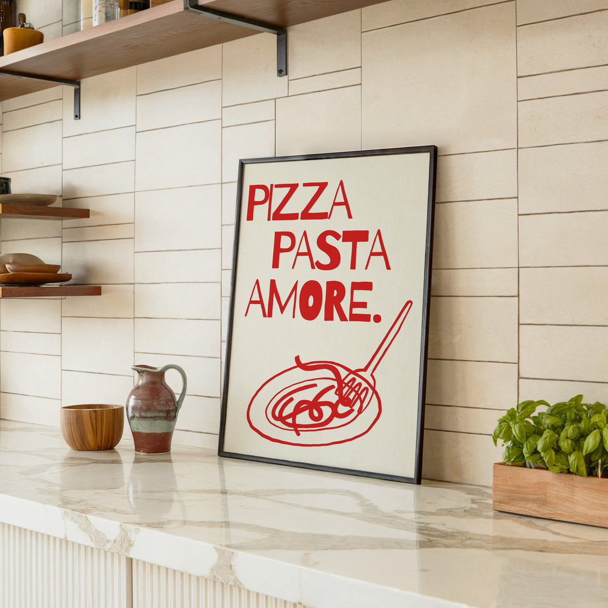 Pizza Pasta Amore print in a black frame leaning on a marble counter in a tiled kitchen