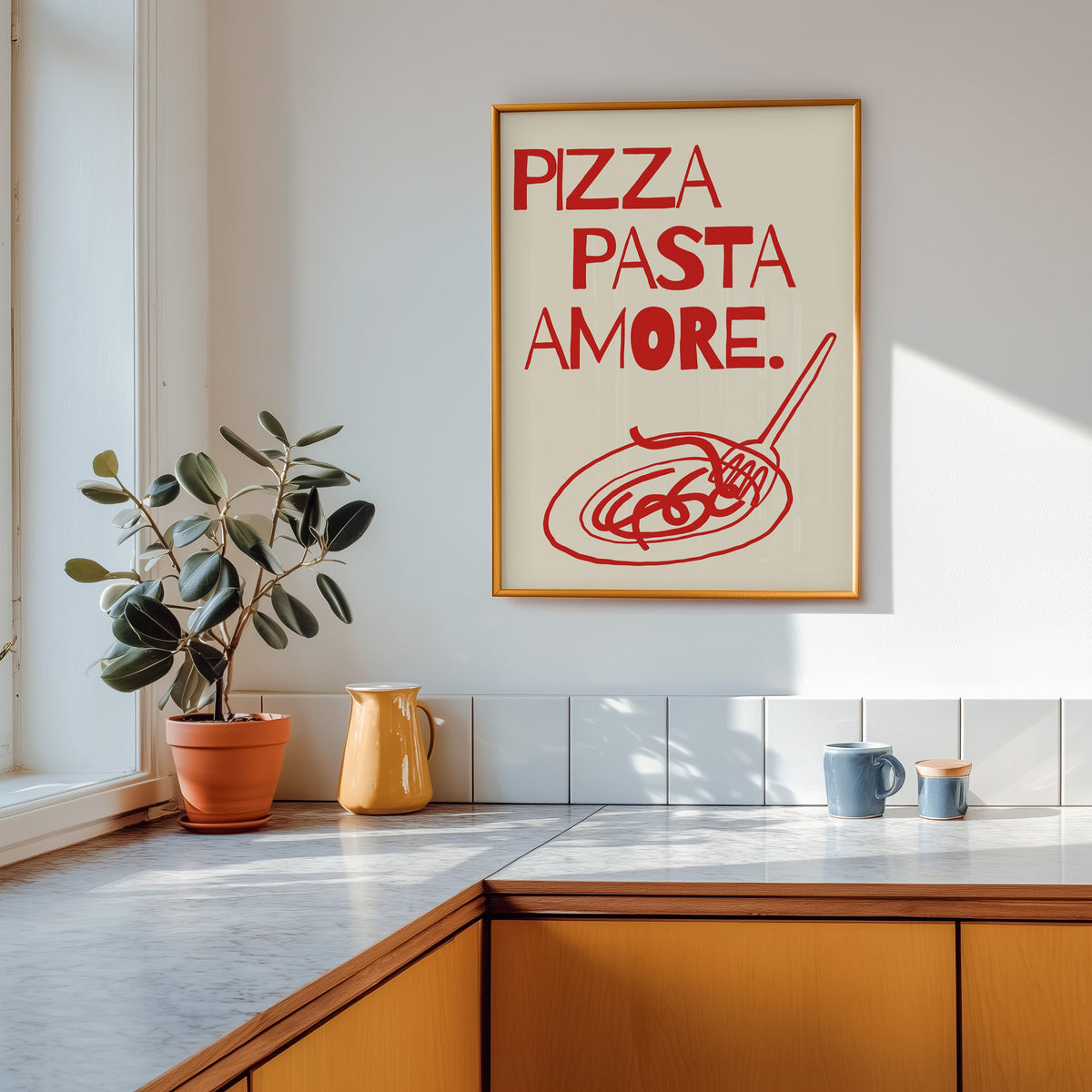 Pizza Pasta Amore print shown in a gold frame above a marble counter in a tan kitchen