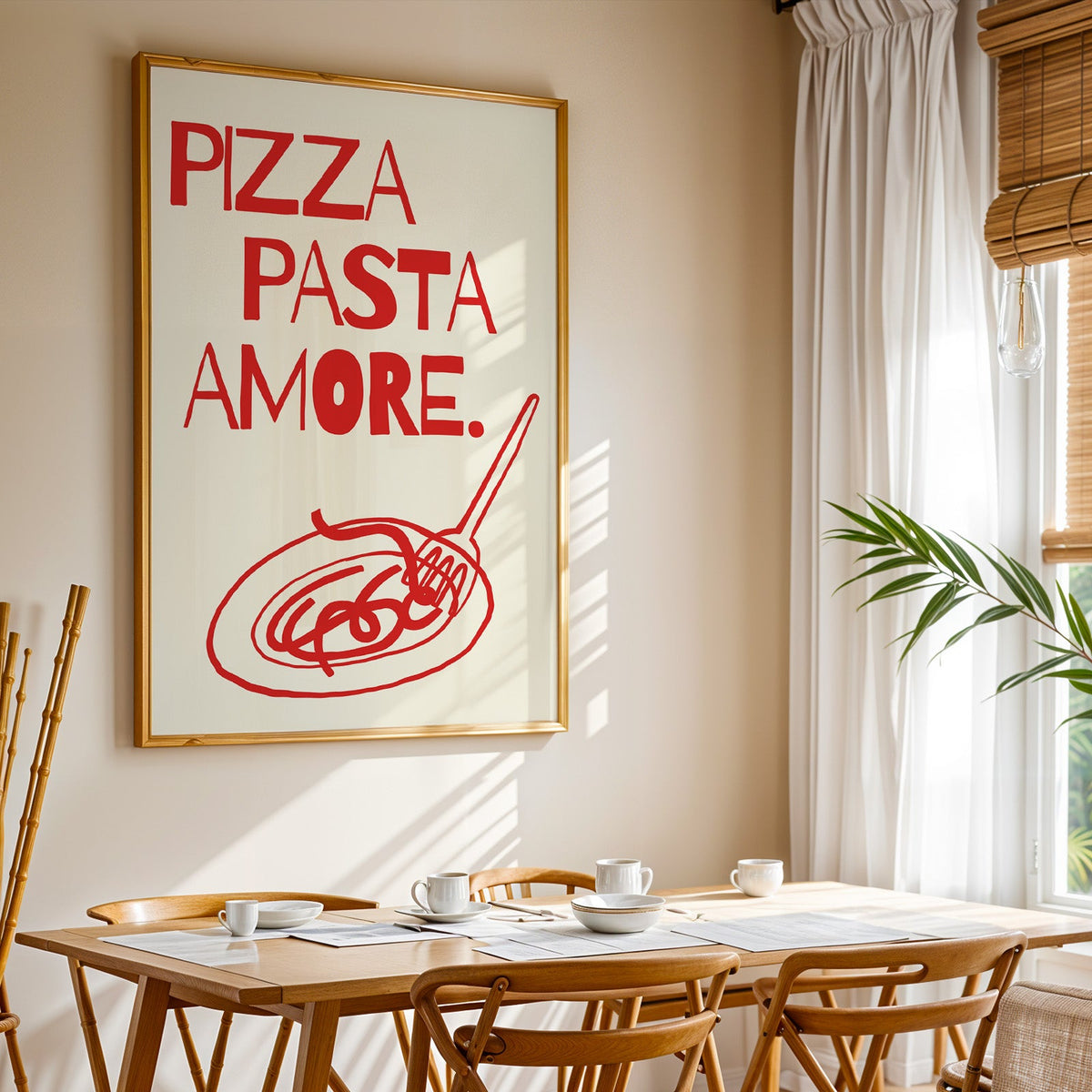 Pizza Pasta Amore print shown in a gold frame above a breakfast table by a curtained window