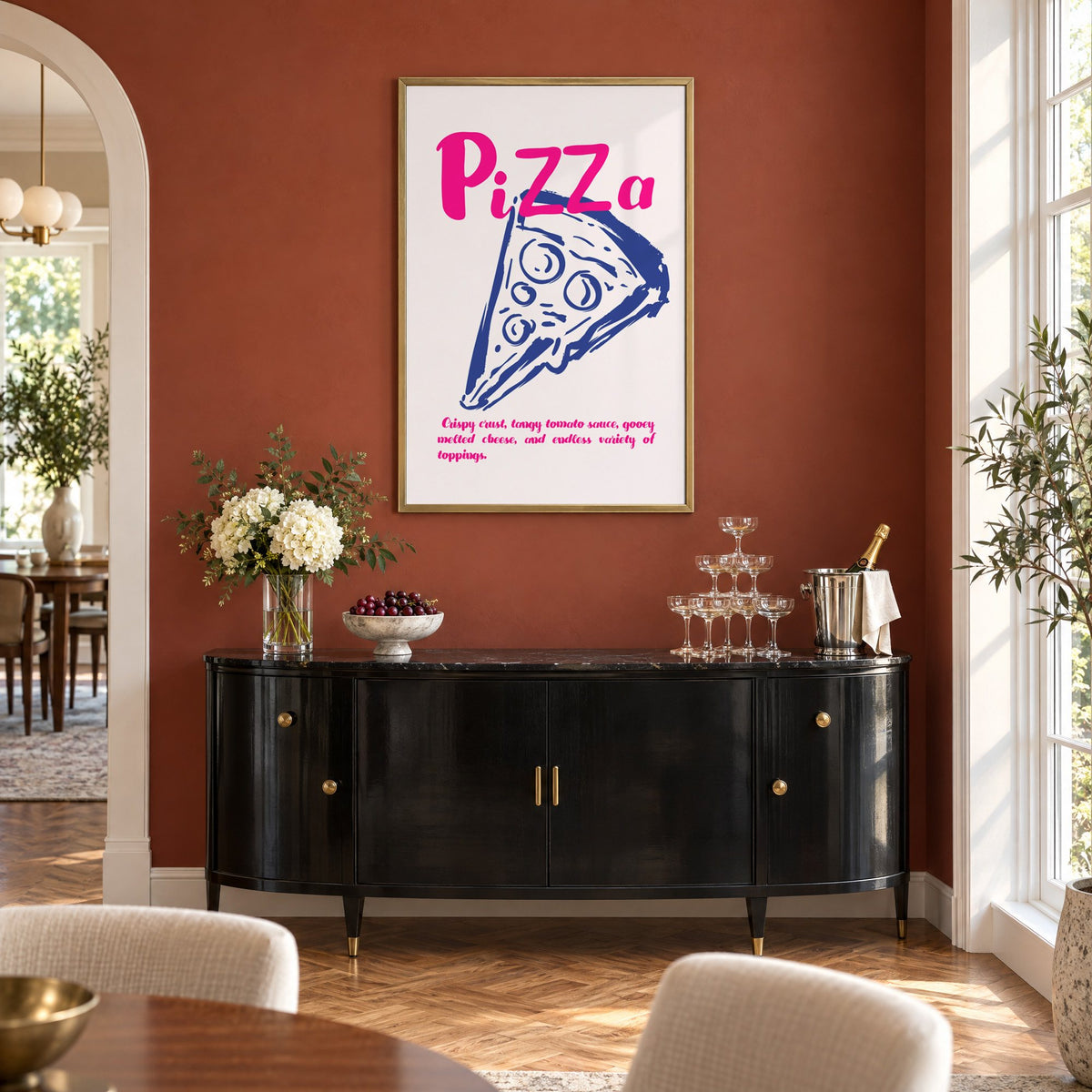 PiZZa pink script pizza slice print in a brass frame on a terracotta wall above a black buffet with a champagne tower