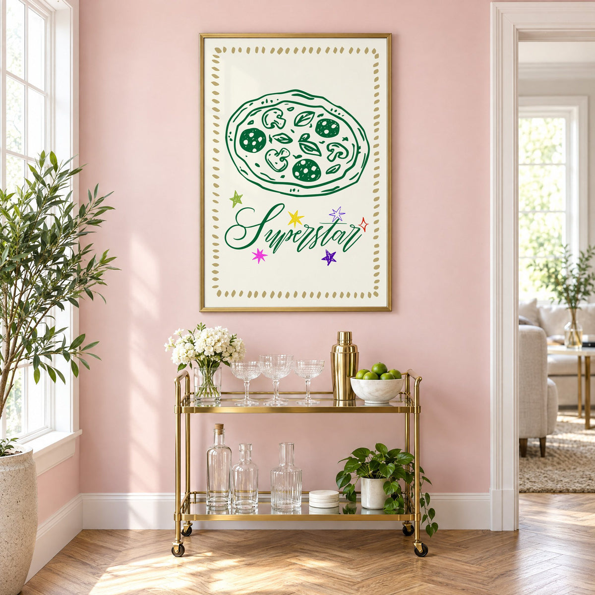 Superstar green pizza and stars print in a brass frame on a blush pink wall above a gold bar cart with glassware
