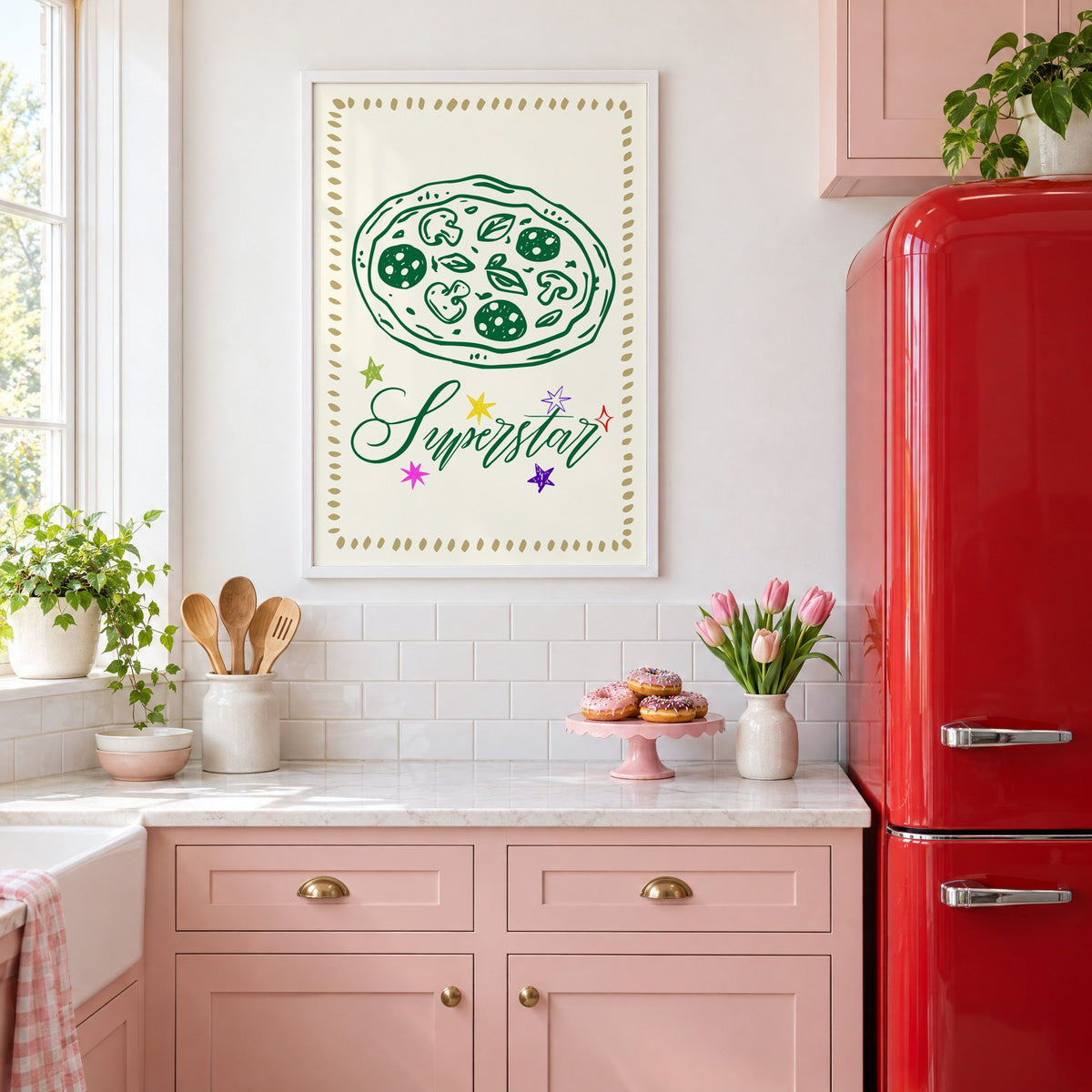 Superstar green pizza and stars print in a white frame above pink cabinets beside a red retro fridge