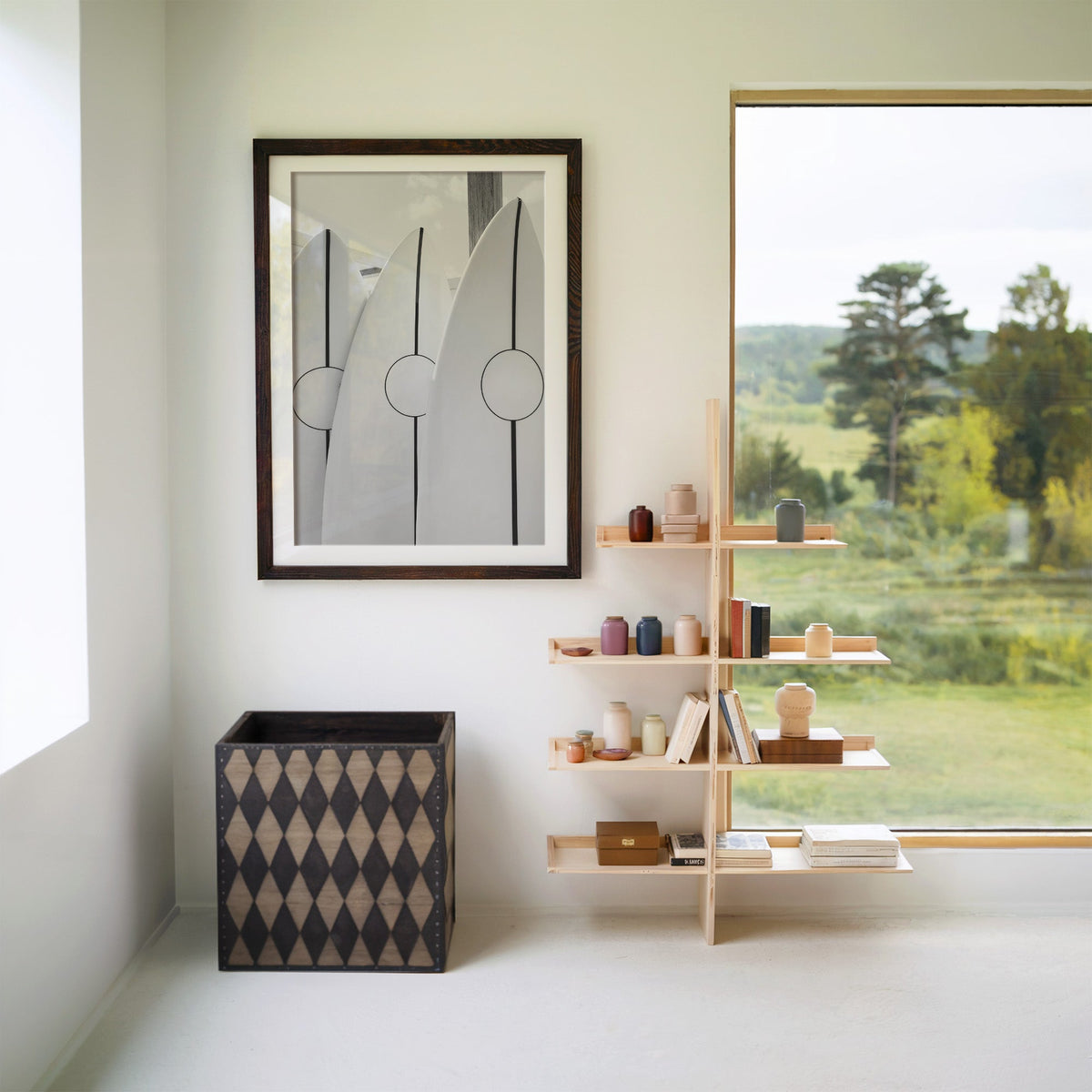 Three white surfboards with black stripes print in a walnut frame with a white mat beside wooden shelves and a garden window