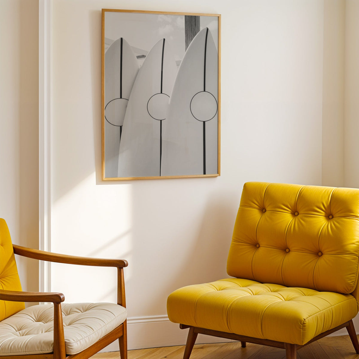 Three white surfboards with black stripes print shown in a gold frame above a mustard yellow tufted armchair