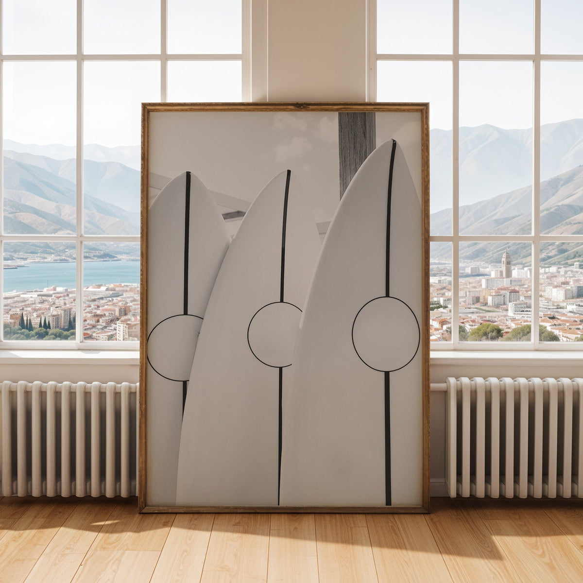 Three white surfboards with black stripes print shown in an antique gold frame by tall windows with a sea view