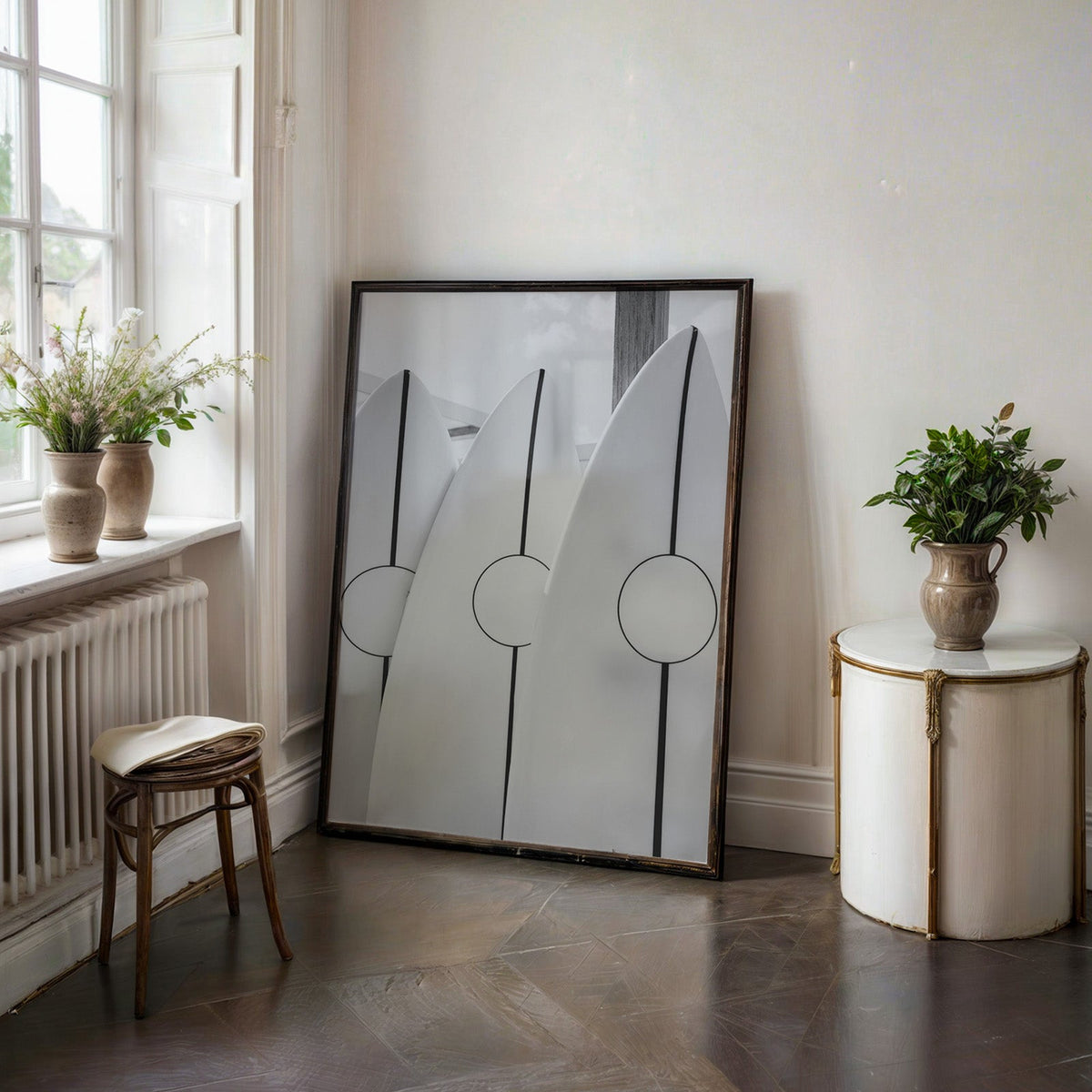 Three white surfboards with black stripes print in a black frame on a dark stone floor beside a white side table