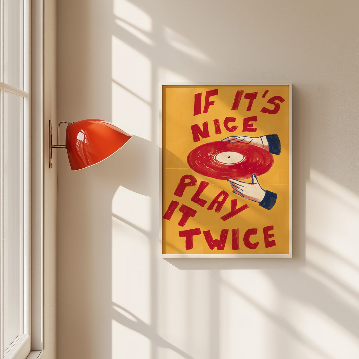 If It's Nice Play It Twice print in a white frame beside a red wall sconce