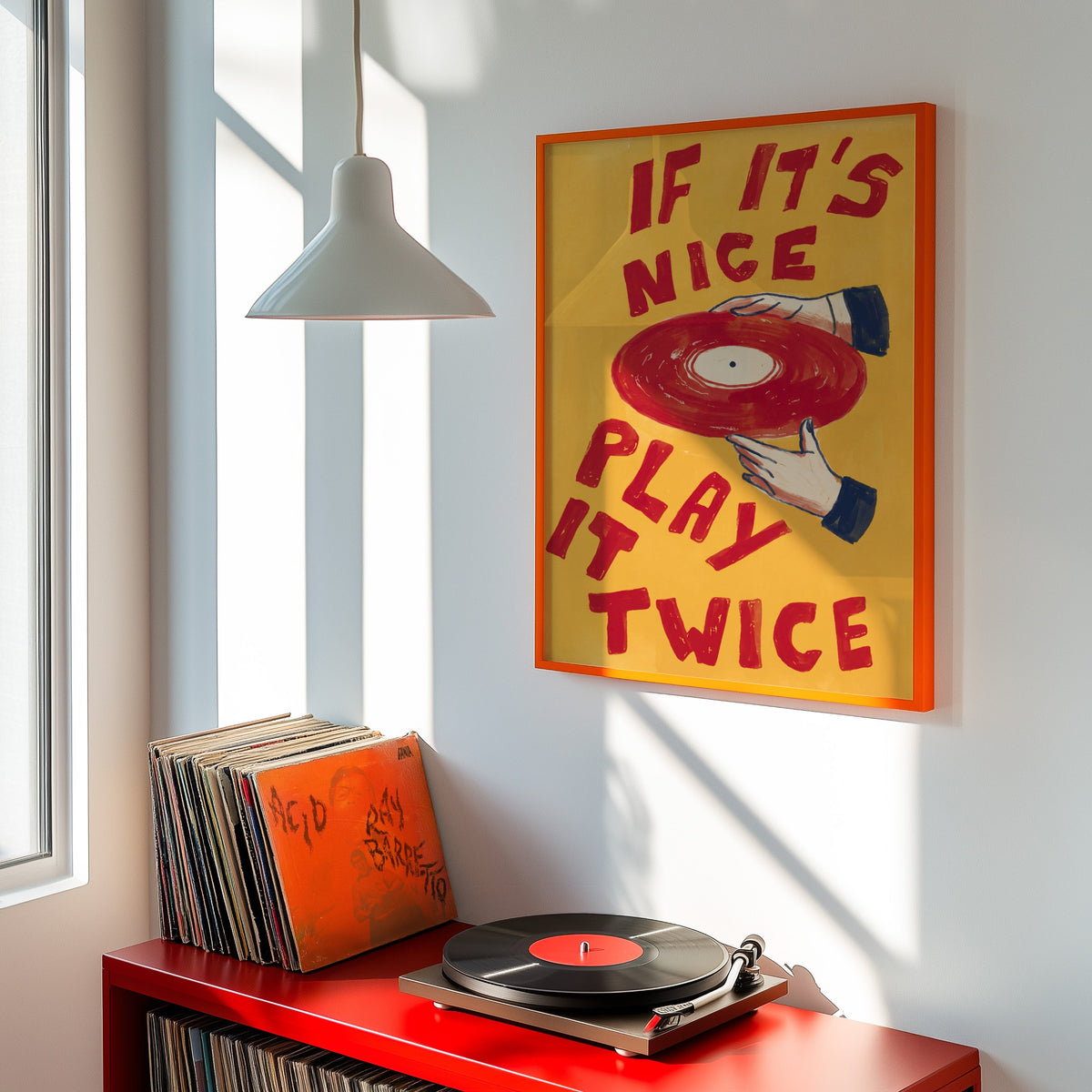 Hands holding red record print shown in an orange frame above a red record cabinet and turntable