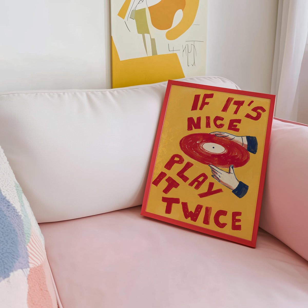 Record collector print shown in a red frame leaning on a blush pink sofa
