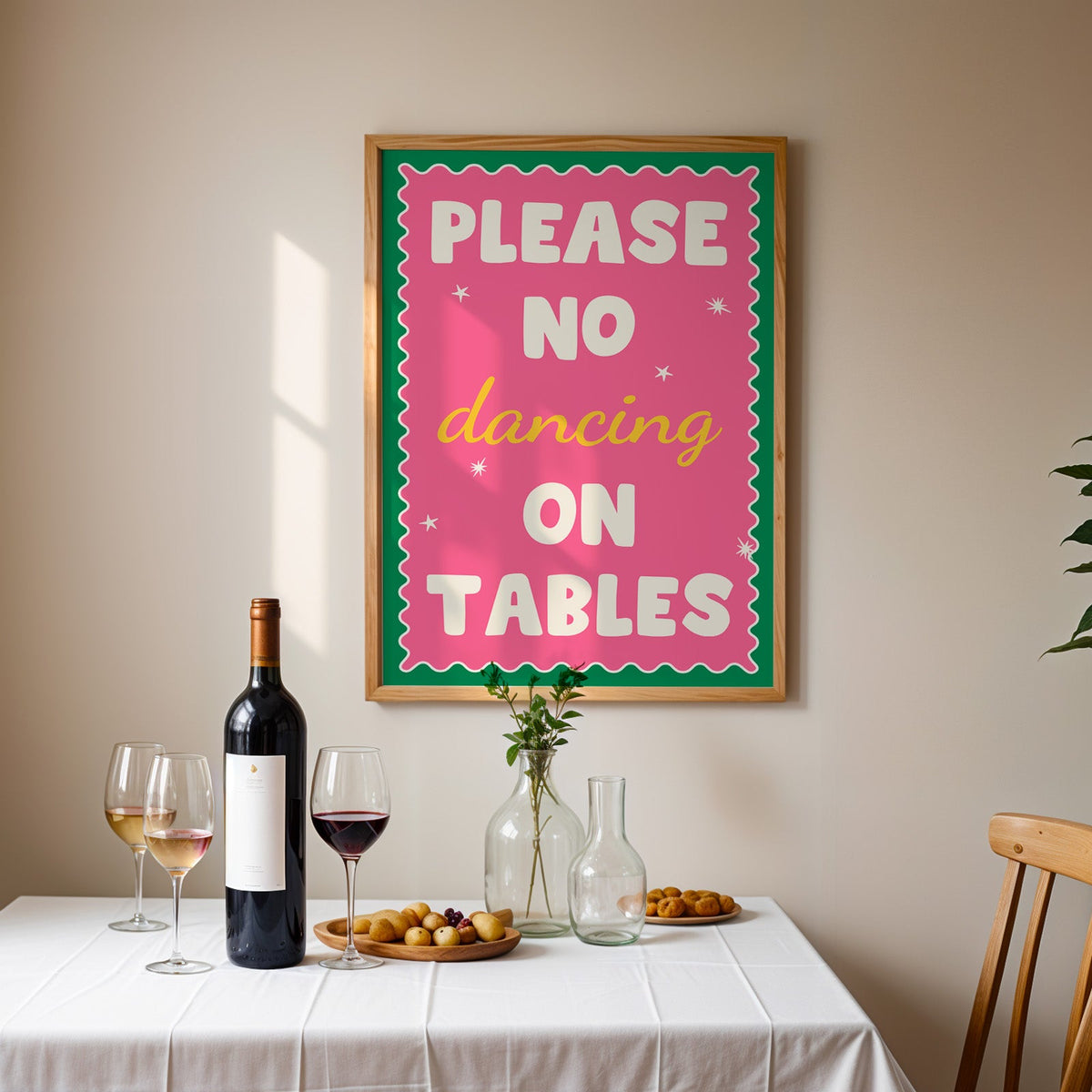 Please no dancing on tables print in an oak frame above a table laid with red wine