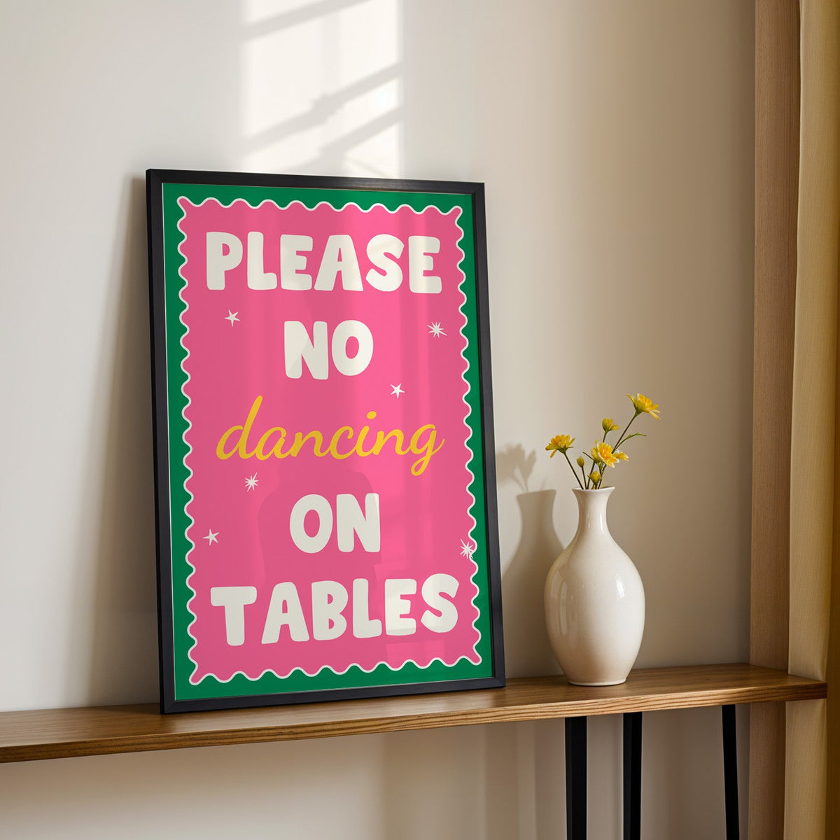 Please no dancing on tables print in a black frame on a console table with daisies