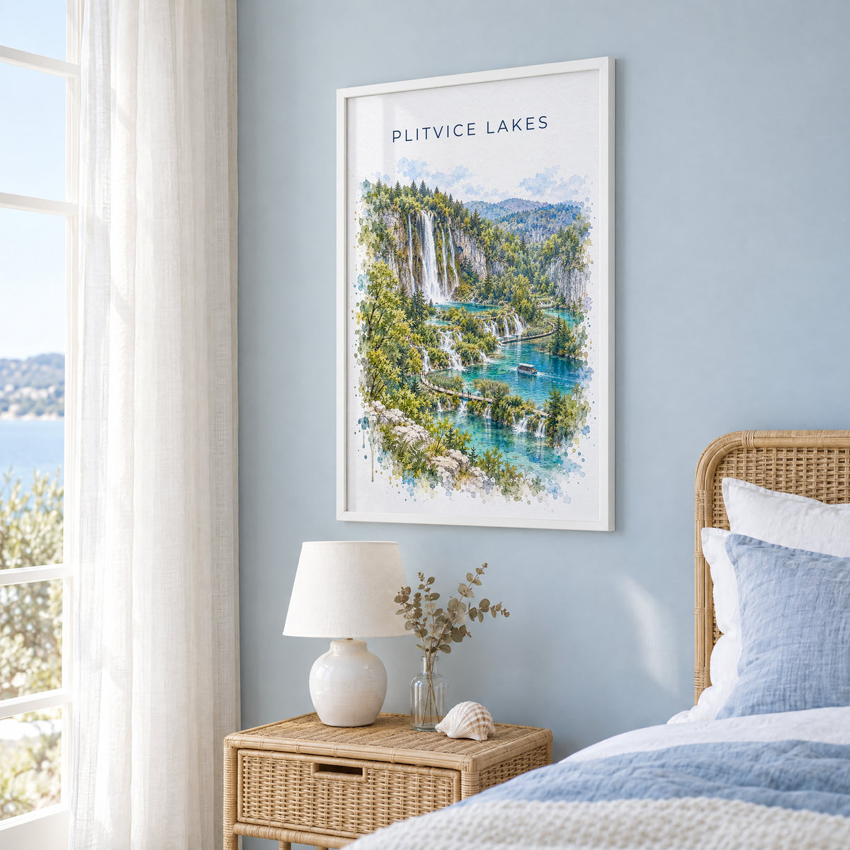 Plitvice Lakes watercolor print in a white frame on a pale blue wall beside a rattan bed in a coastal bedroom