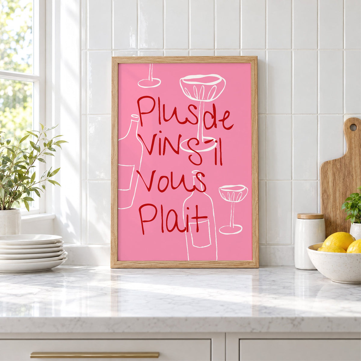 Plus de Vin handwritten pink print in an oak frame leaning on a marble counter by white tiles and lemons