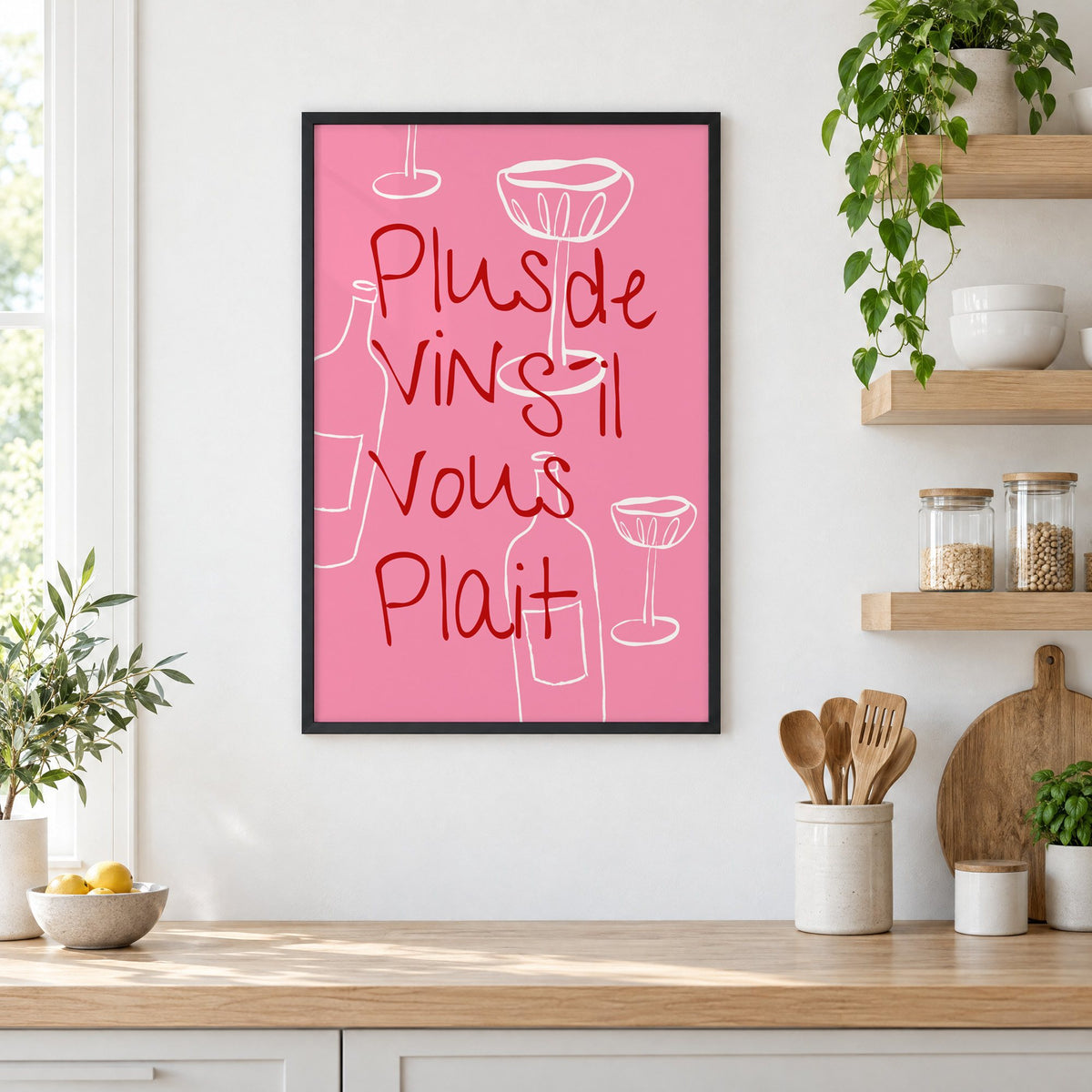 Plus de Vin handwritten pink print in a black frame in a white kitchen beside open wood shelves and glass jars