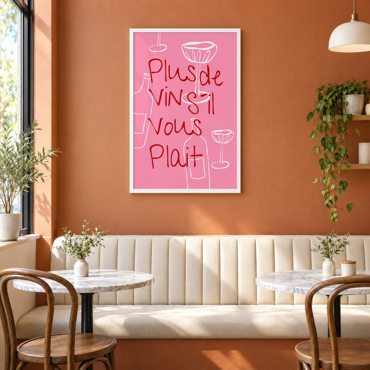 Plus de Vin handwritten pink print in a white frame above a cream banquette on a terracotta cafe wall
