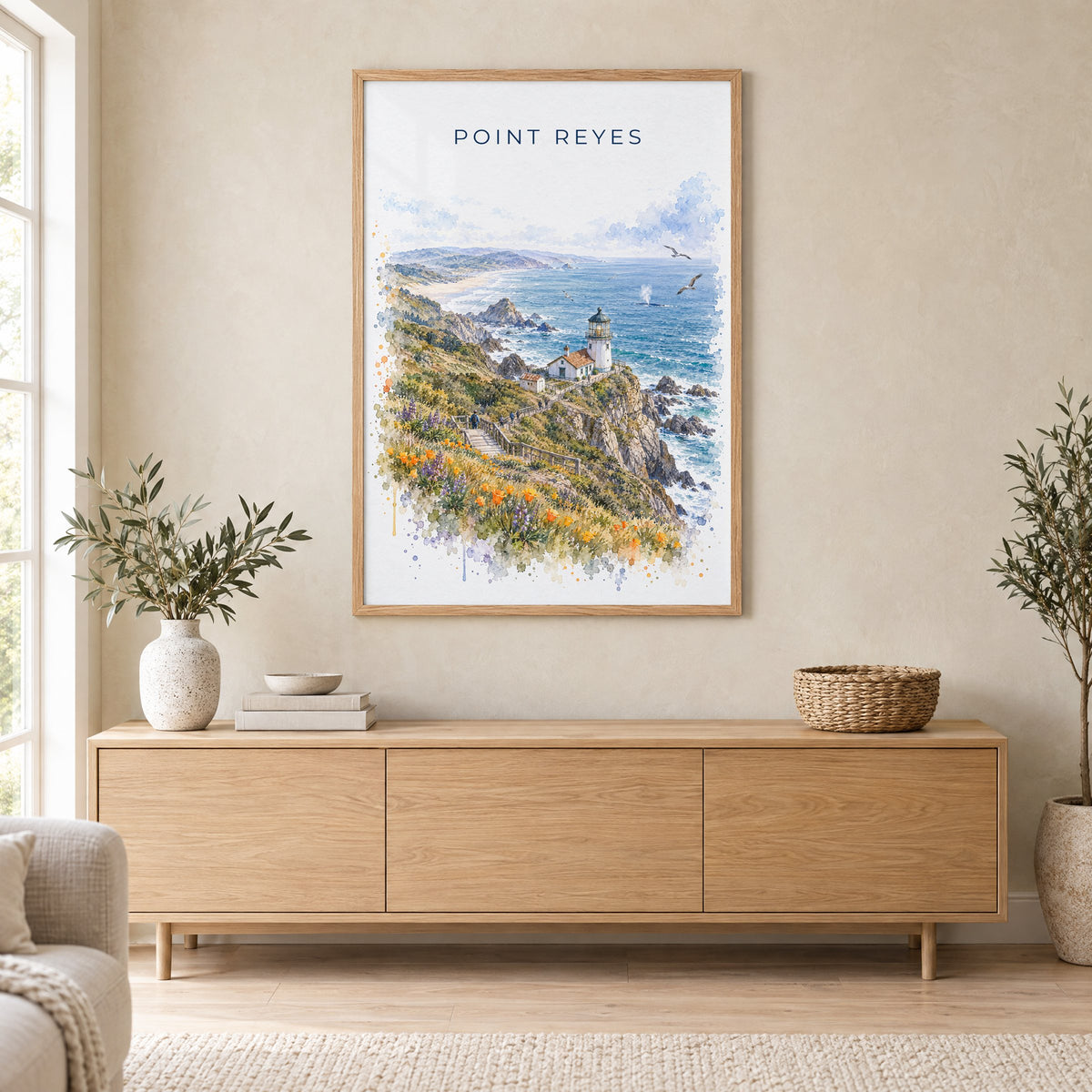 Point Reyes watercolor print in an oak frame above a light wood sideboard in a Scandinavian living room