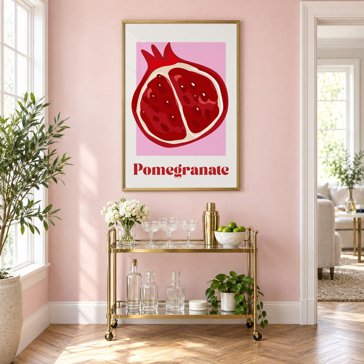 Pomegranate half bold serif pink panel print in a brass frame on a blush pink wall above a gold bar cart with glassware