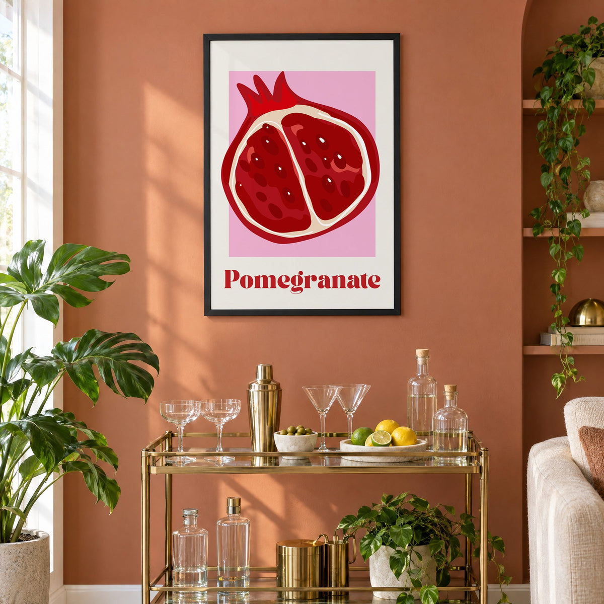 Pomegranate half bold serif pink panel print in a black frame on a terracotta wall above a brass bar cart with coupes and citrus