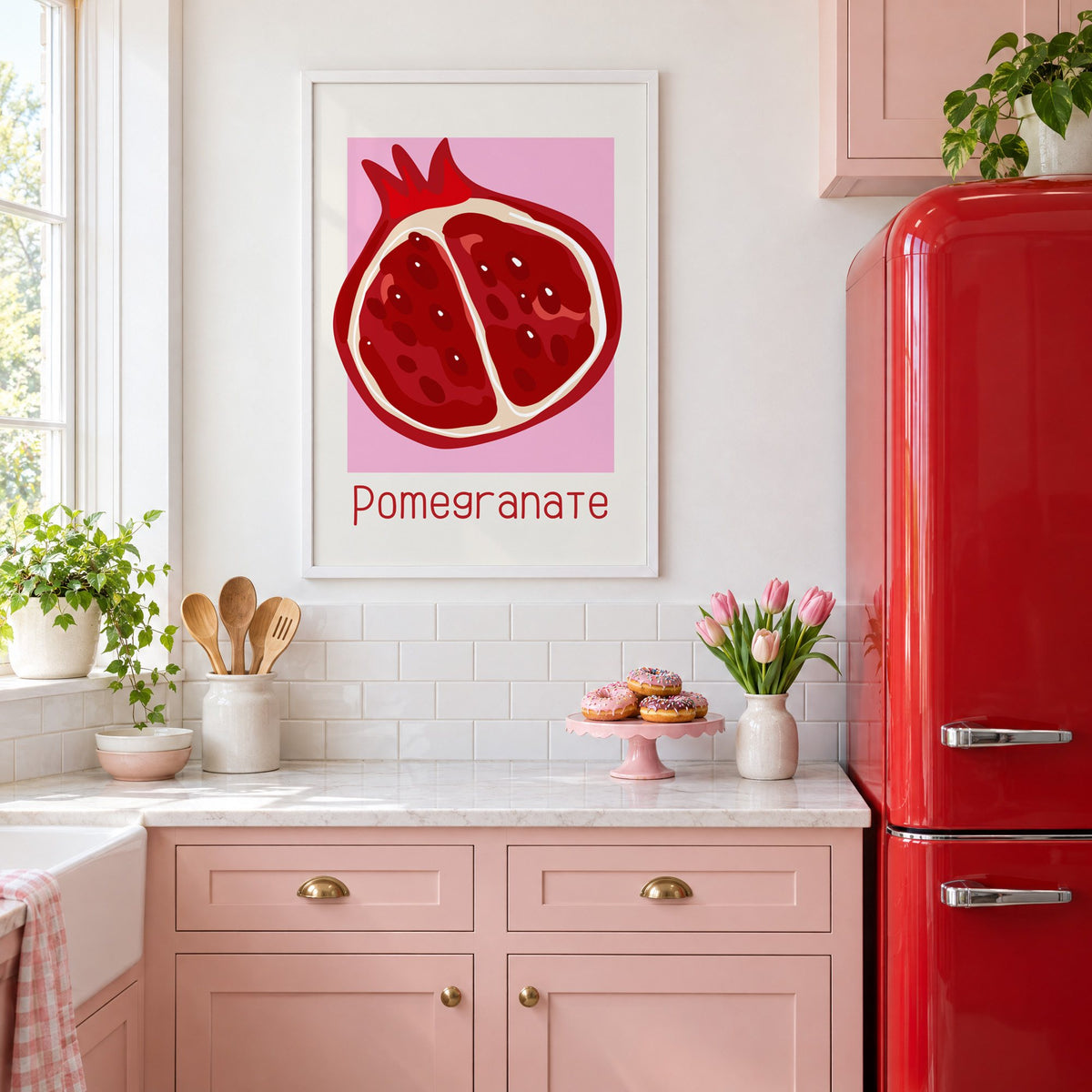 Pomegranate thin lettering halved fruit print in a white frame above pink cabinets beside a red retro fridge