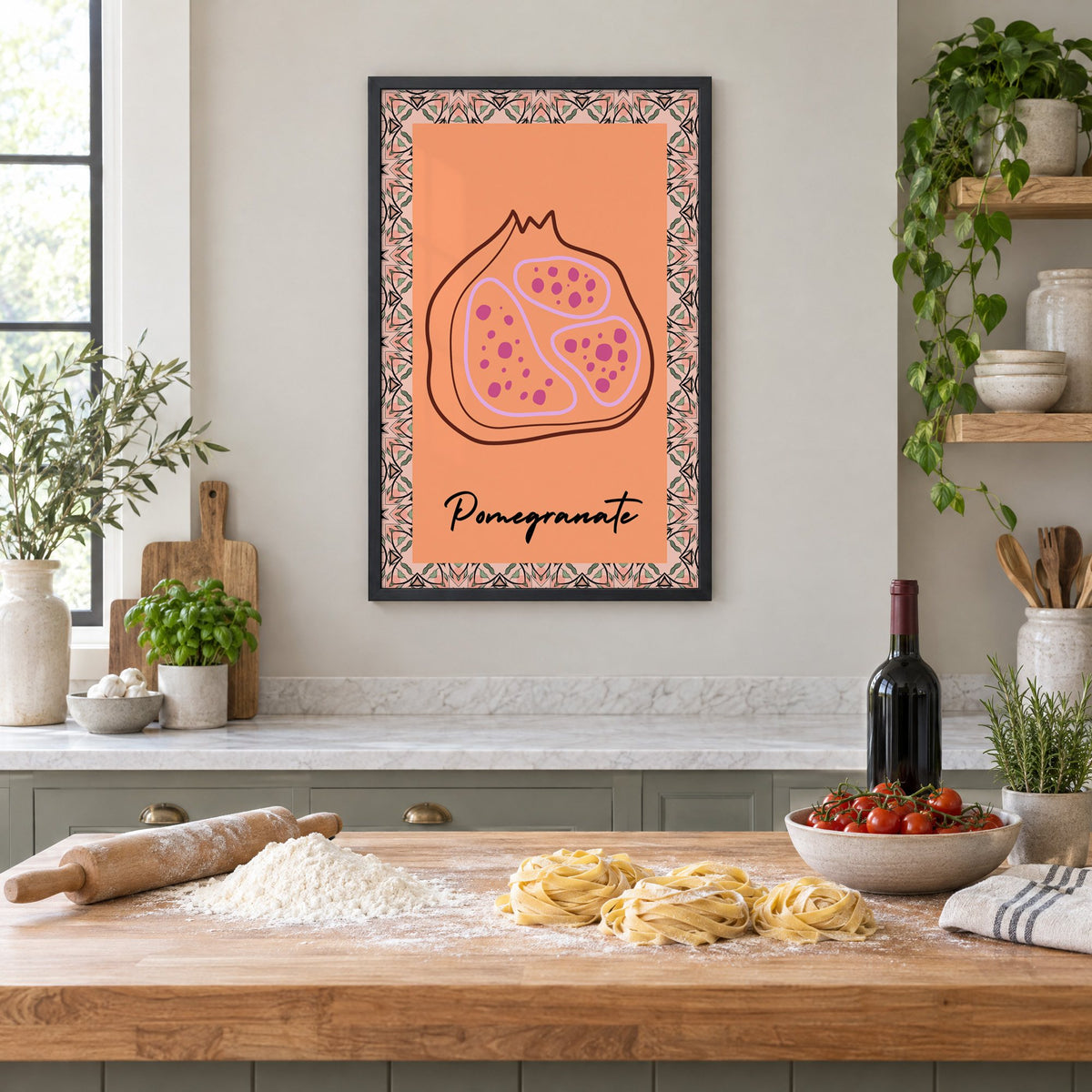 Pomegranate line-art kaleidoscope border print in a black frame above a butcher-block island with fresh pasta, flour and cherry tomatoes