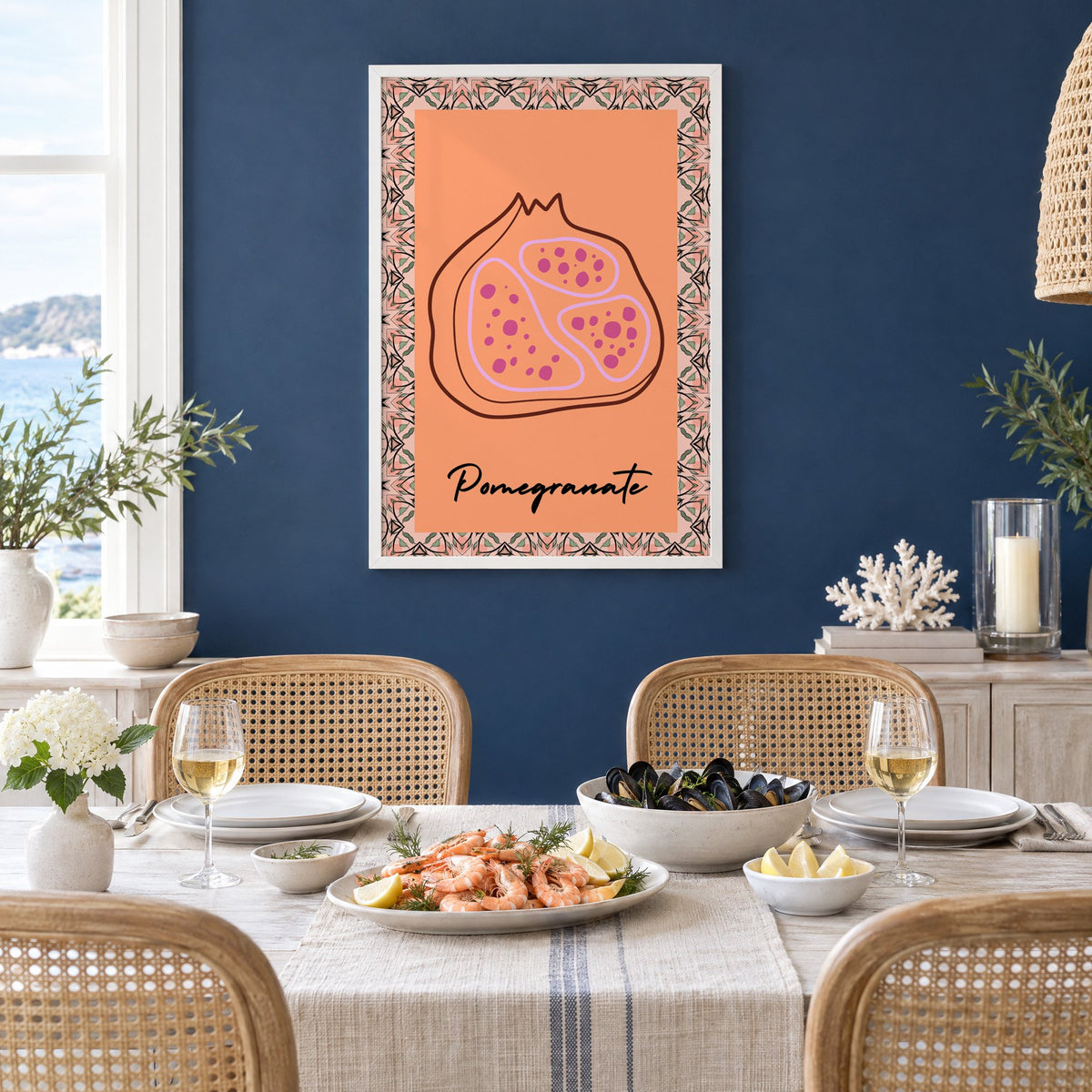Pomegranate line-art kaleidoscope border print in a white frame on a navy wall above a dining table set with shrimp and mussels