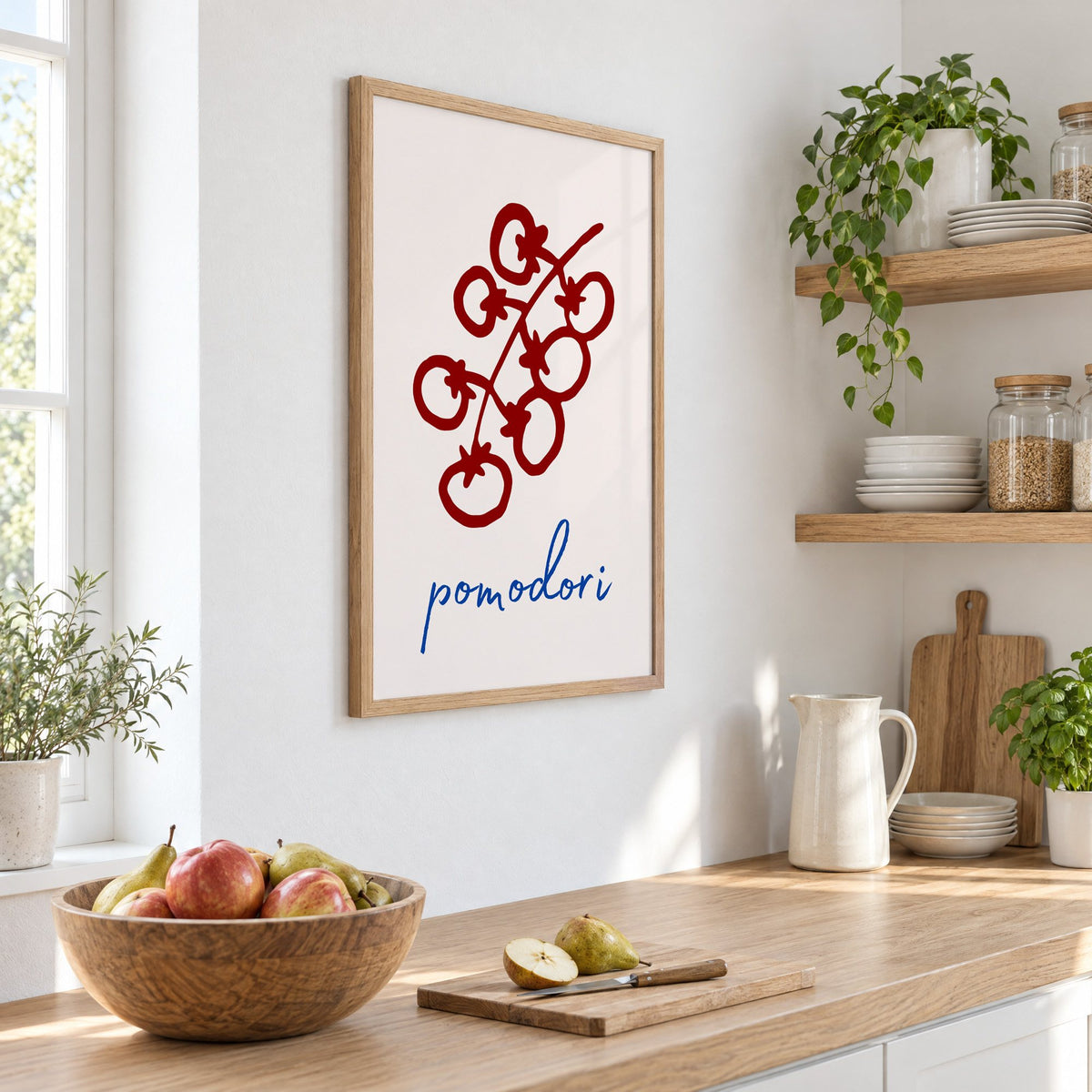 pomodori red cherry tomato vine print in an oak frame on a white kitchen wall above a counter with apples and pears, seen at an angle
