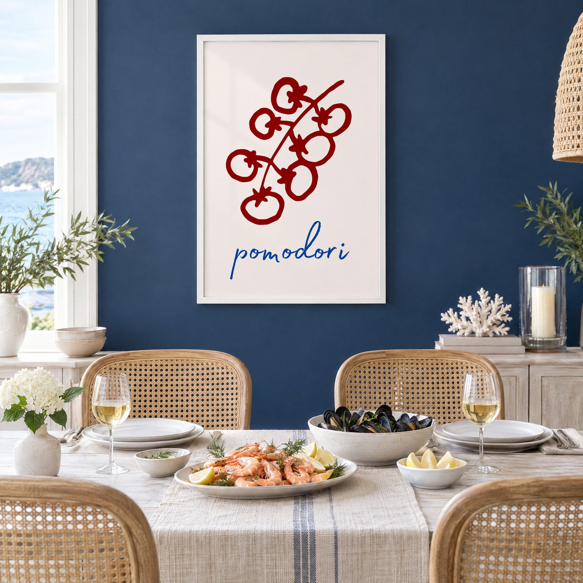 pomodori red cherry tomato vine print in a white frame on a navy wall above a dining table set with shrimp and mussels