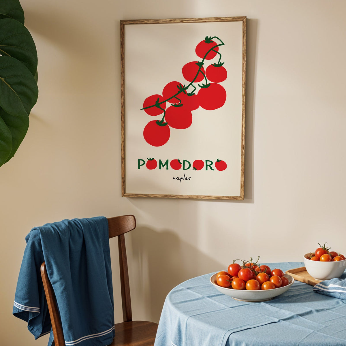 Pomodoro Naples tomato vine print in an oak frame above a blue linen table with tomatoes
