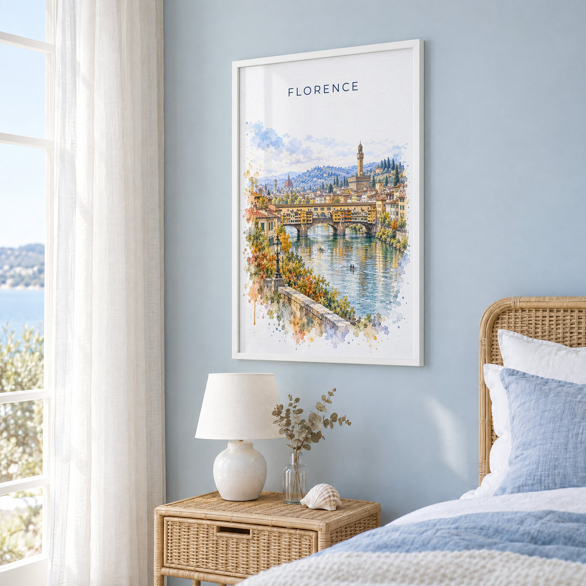 Ponte Vecchio watercolor print in a white frame on a pale blue wall beside a rattan bed in a coastal bedroom