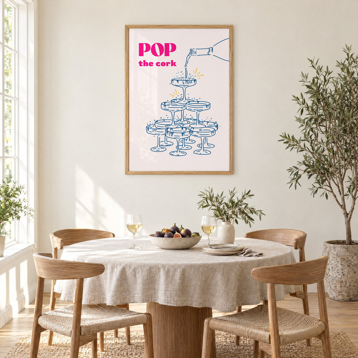 Pop the cork champagne tower print in an oak frame above a round linen-covered dining table with figs and wine
