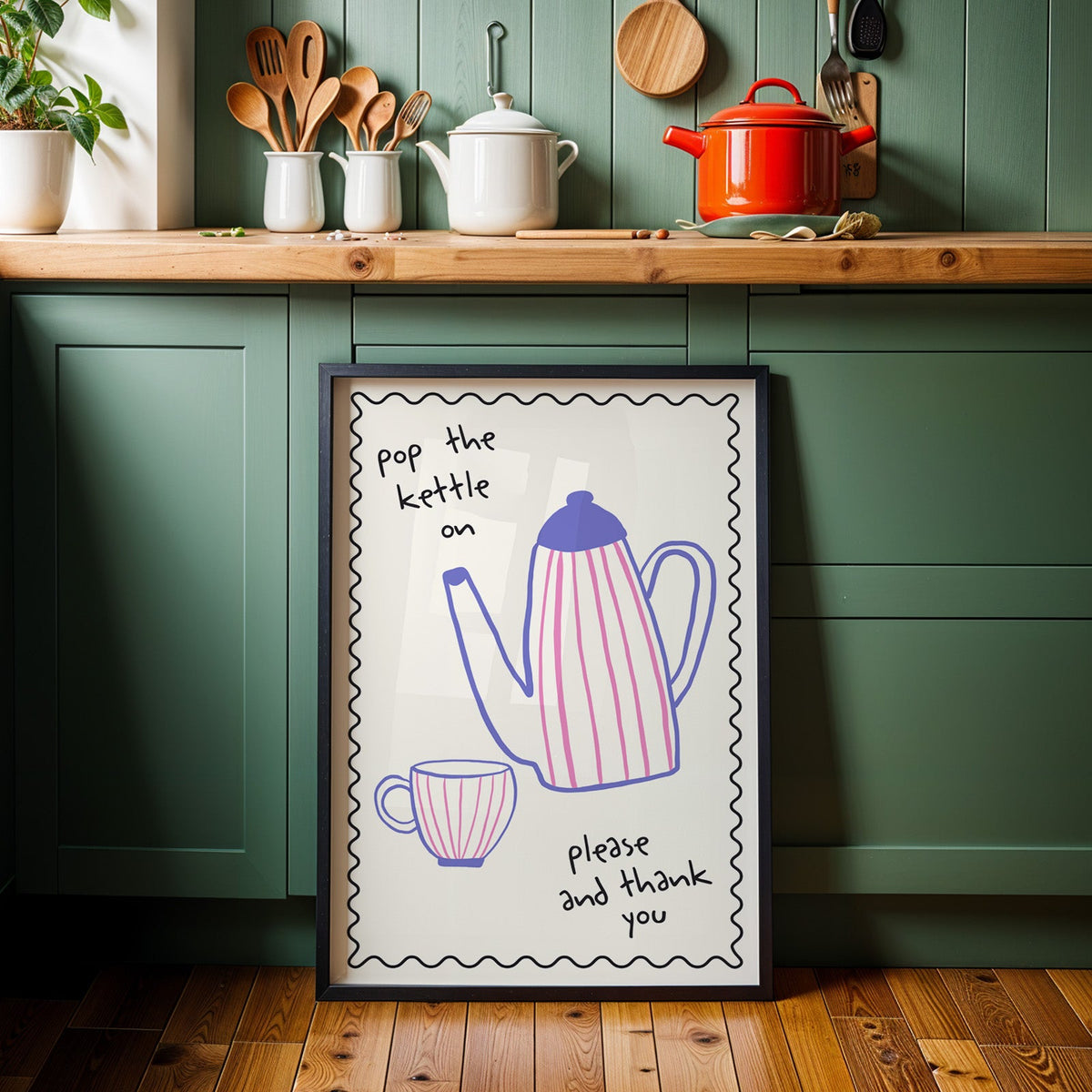 Pop the kettle on teapot print in a black frame against sage green kitchen cabinets
