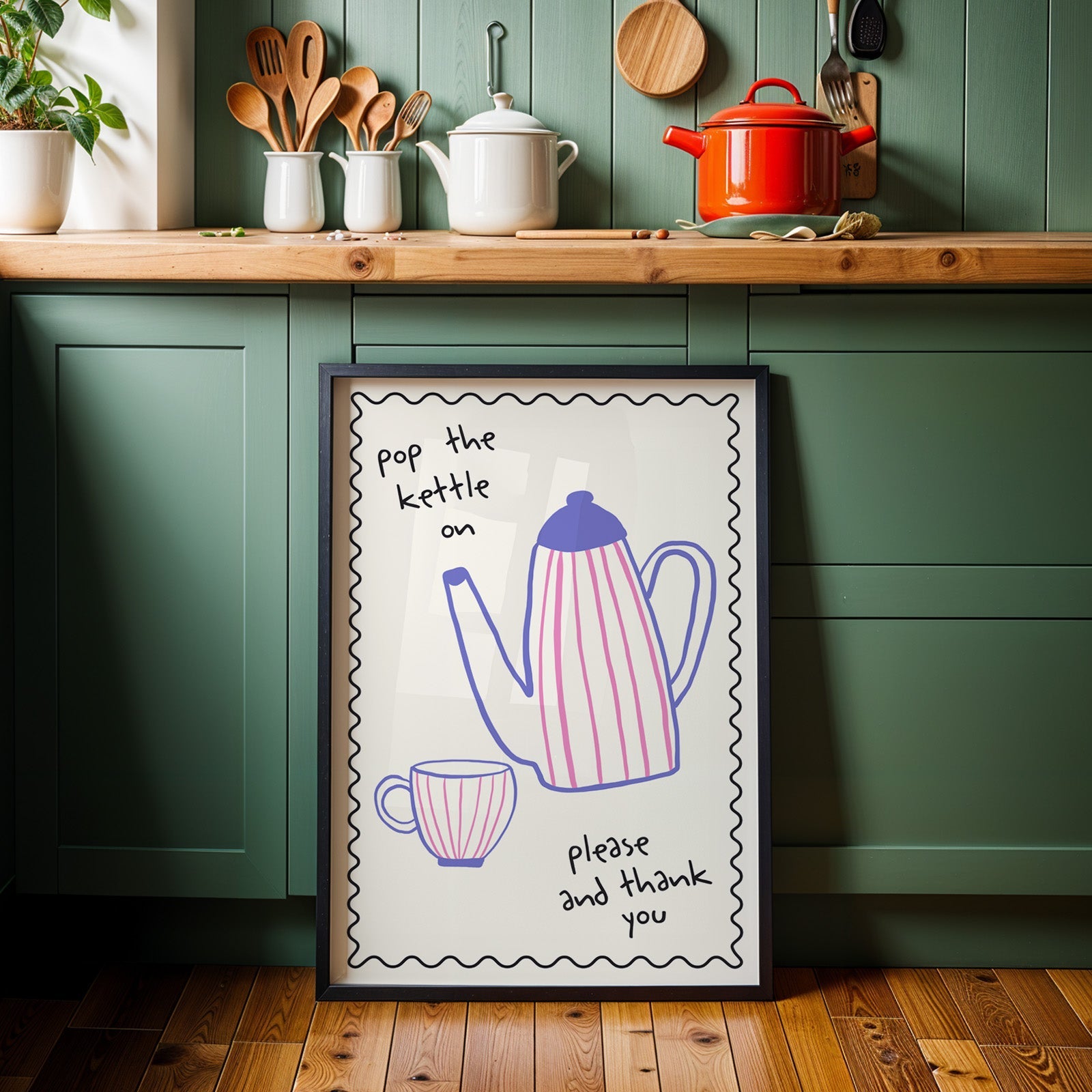 Pop the kettle on teapot print in a black frame against sage green kitchen cabinets