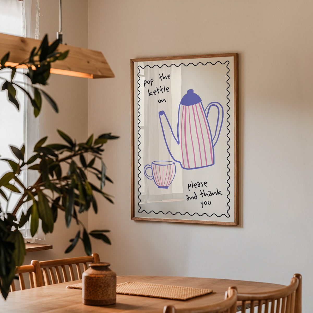 Pop the kettle on teapot print in a walnut frame above a table beside an olive tree