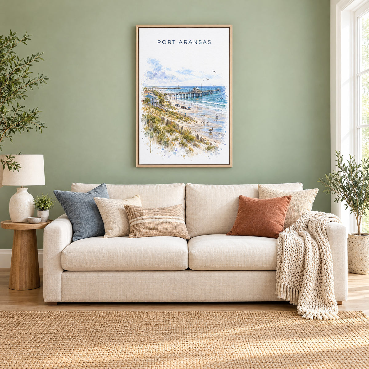 Port Aransas watercolor print as a natural floater canvas above a cream linen sofa on a sage green wall