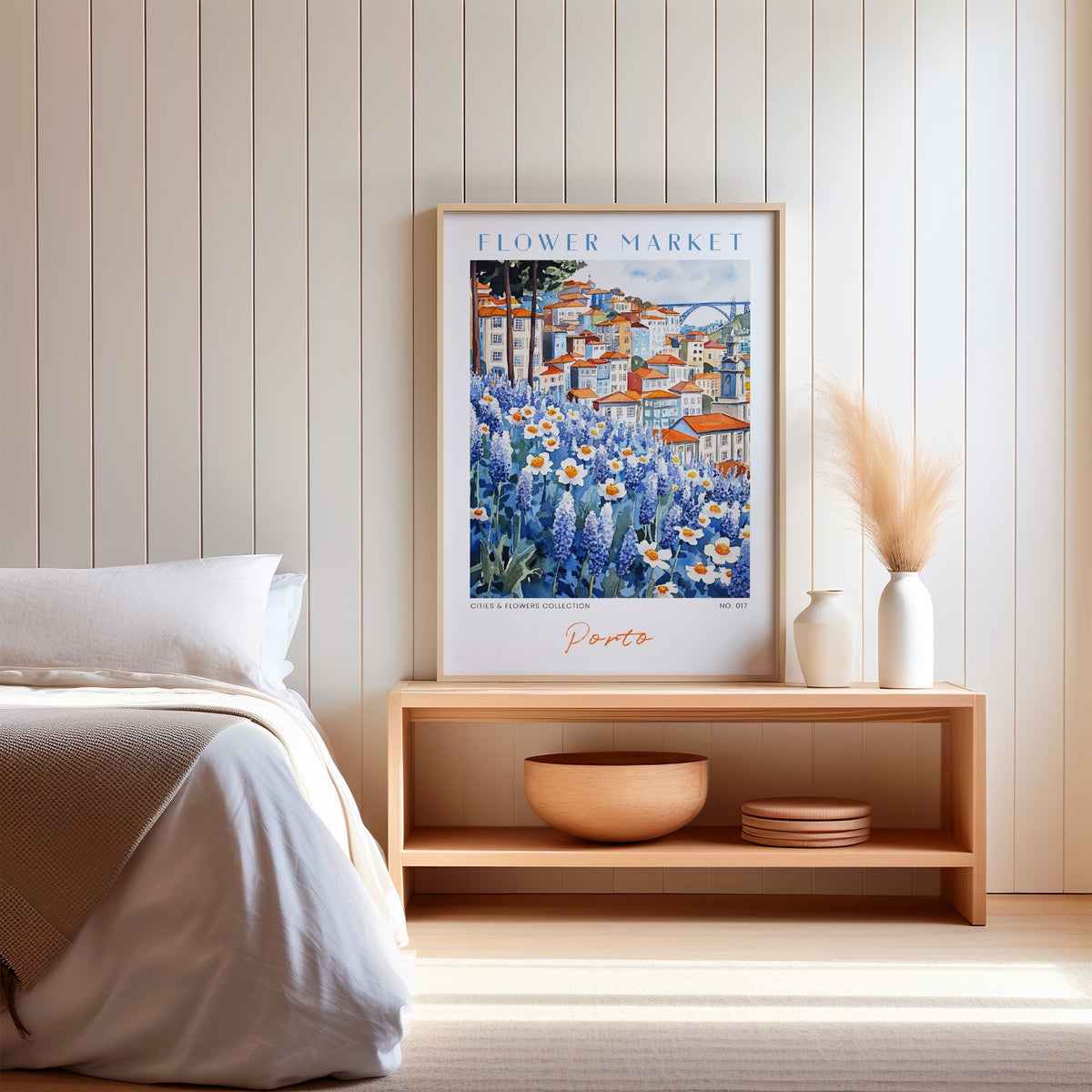 Porto flower market print in an oak frame on a wood bench against a white shiplap bedroom wall with pampas grass
