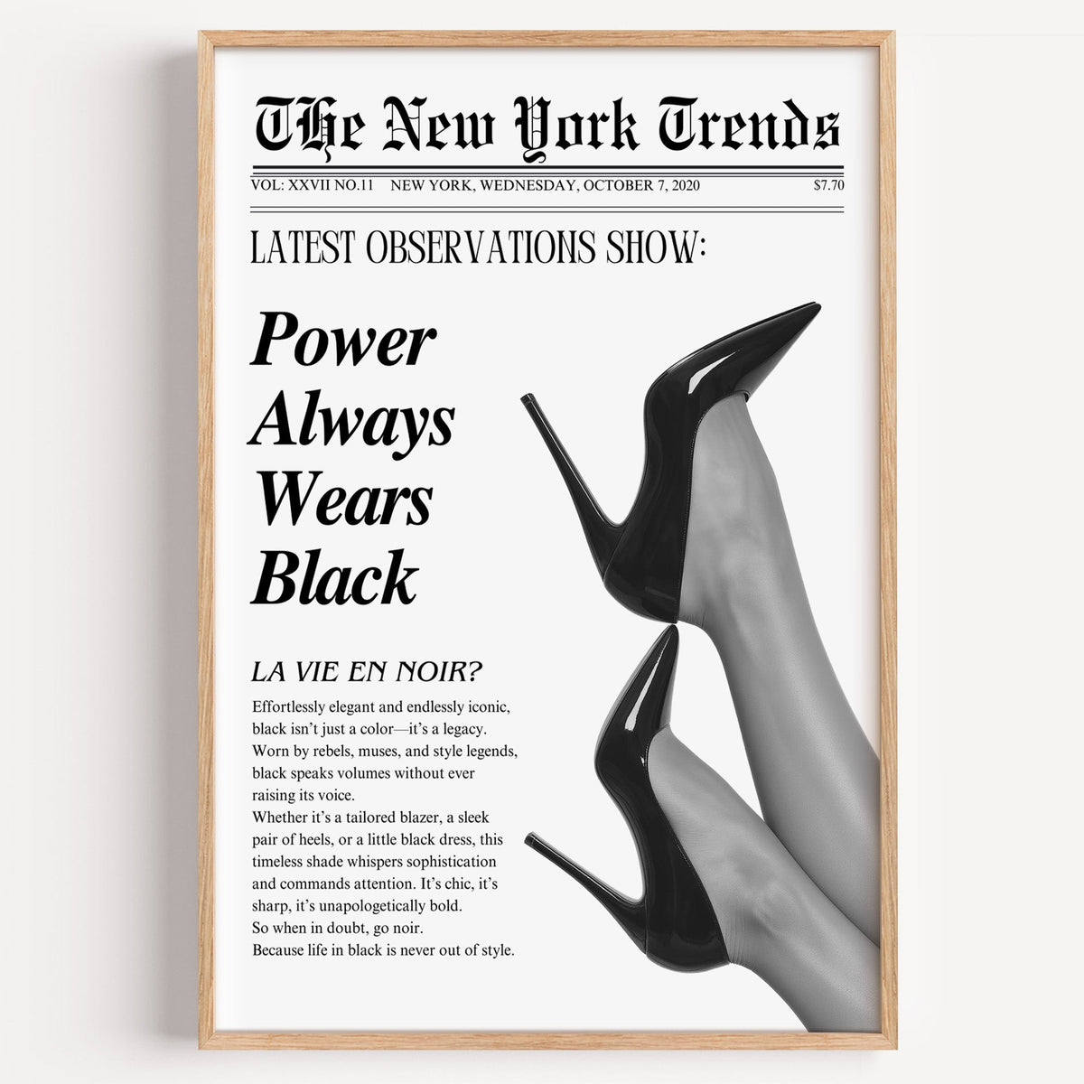 Two pairs of black heels mock newspaper print in a light oak frame on a plain white wall
