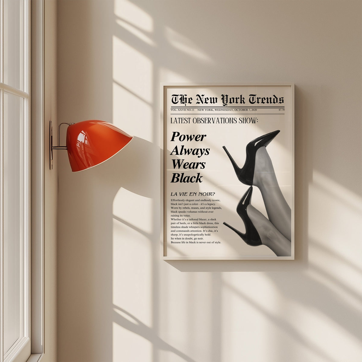 Two pairs of black heels mock newspaper print in a white frame on a sunlit wall beside a red sconce